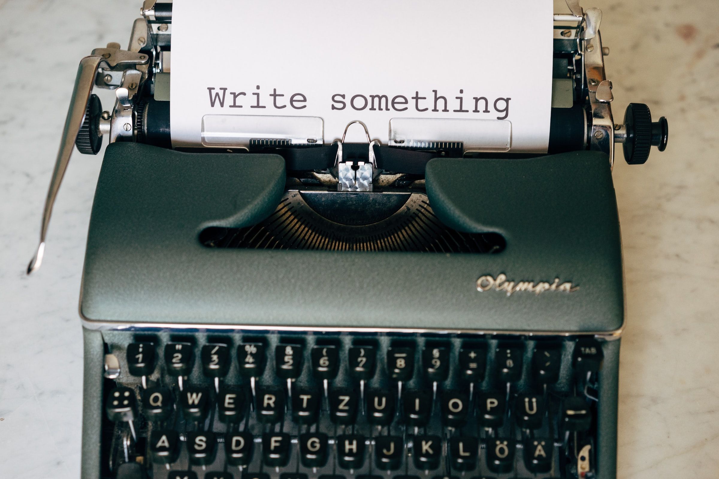 A photo of a typewriter with the words ‘Write something’ on the paper in the typewriter roll