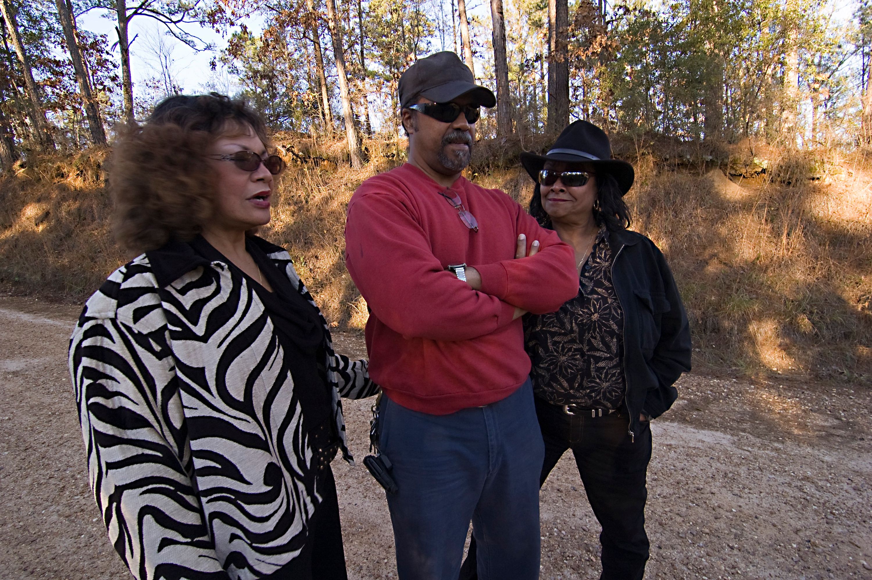 From left to right, Shirley Walker Wright, Clifton Walker, Jr. and Catherine Walker Jones stand in the middle of Poor House Road, where their father was murdered in 1964. Photo by Ben Greenberg