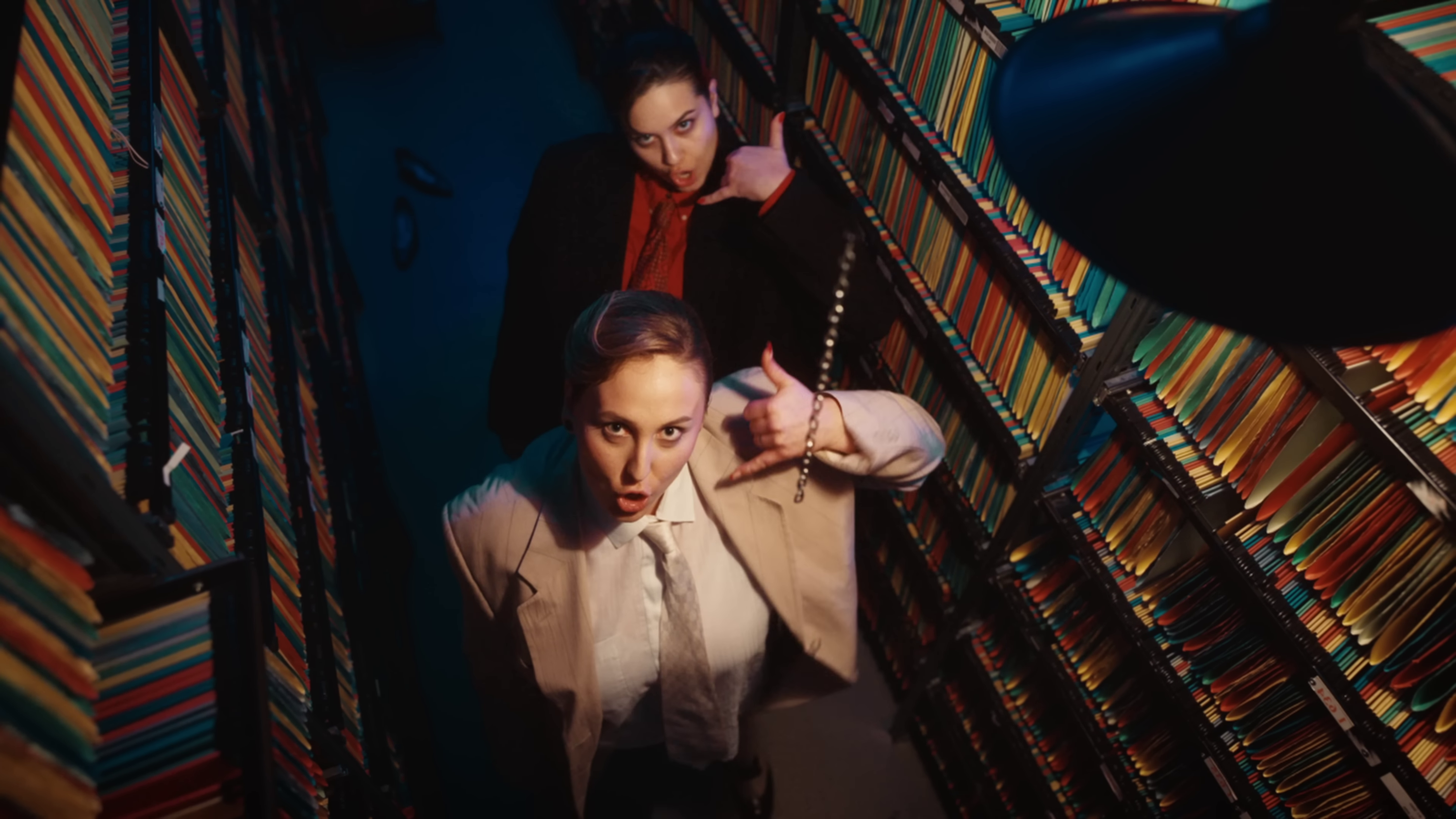 image of Teya and Salena wearing suits, surrounded by stacks of files