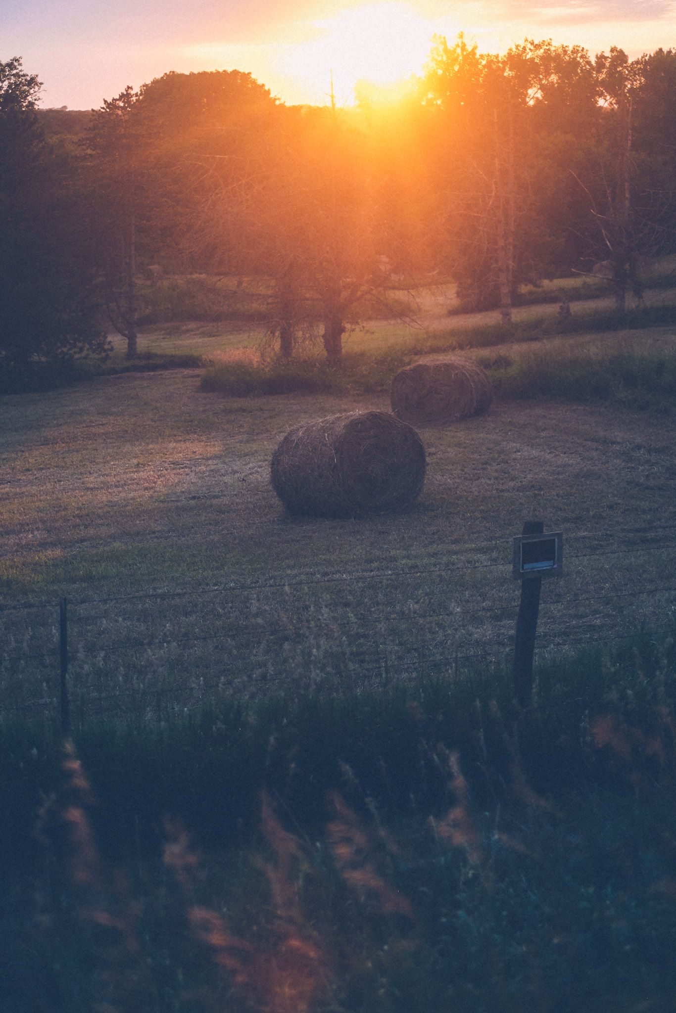 A couple bales of hay lie in a Nebraska field at sunset.