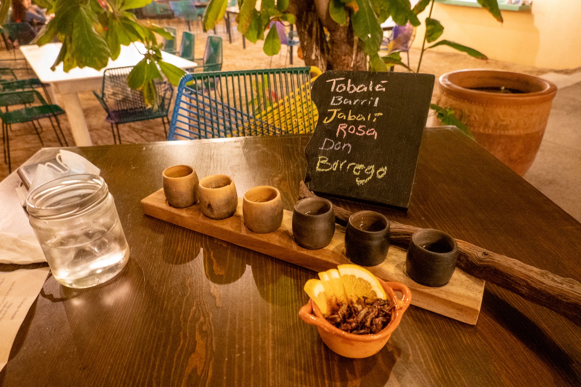 Mezcal tasting flight served with orange slices and fried grasshoppers to reset the palette between tasting.