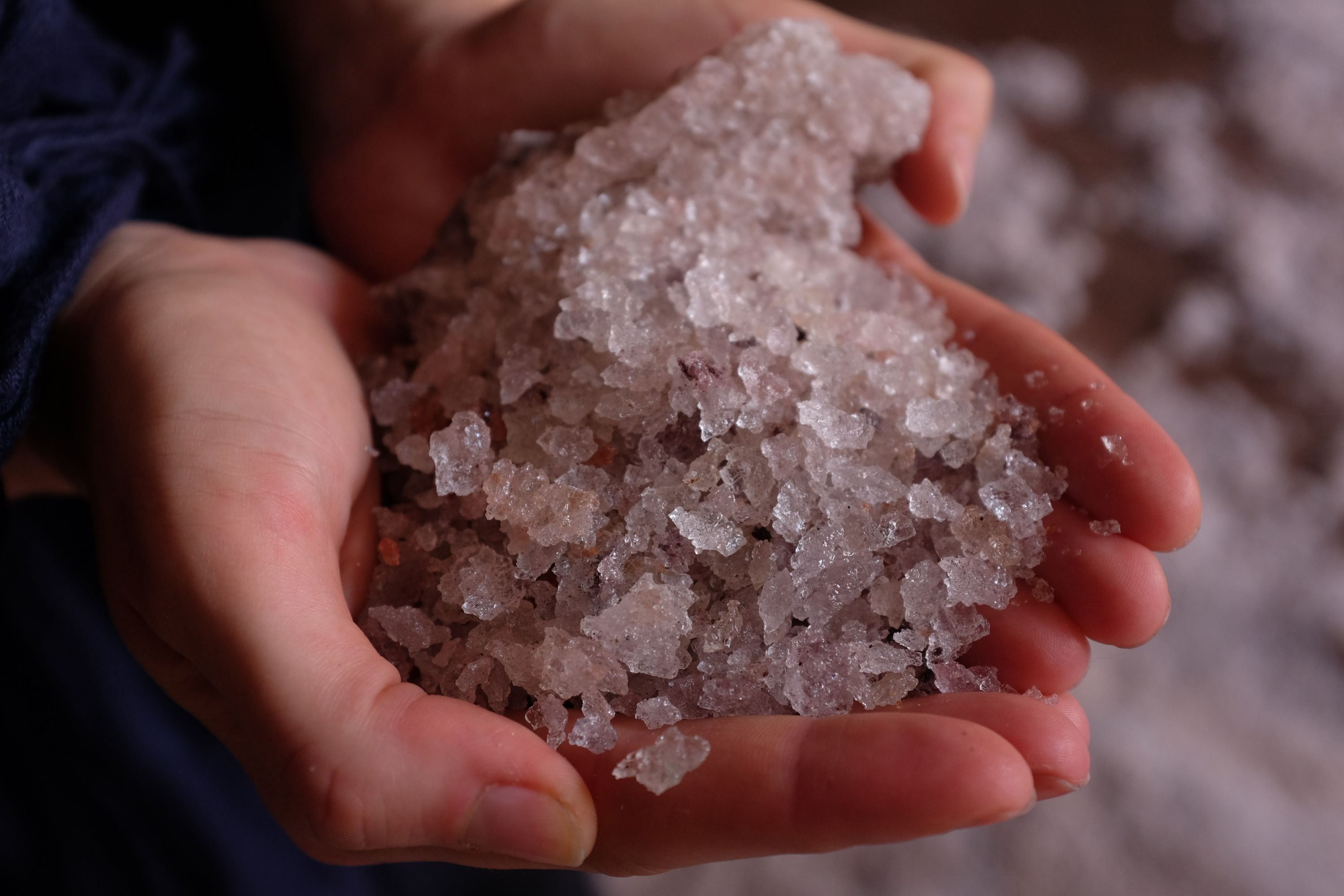 Closeup of a person holding a large handful of salt crystals in their hands.