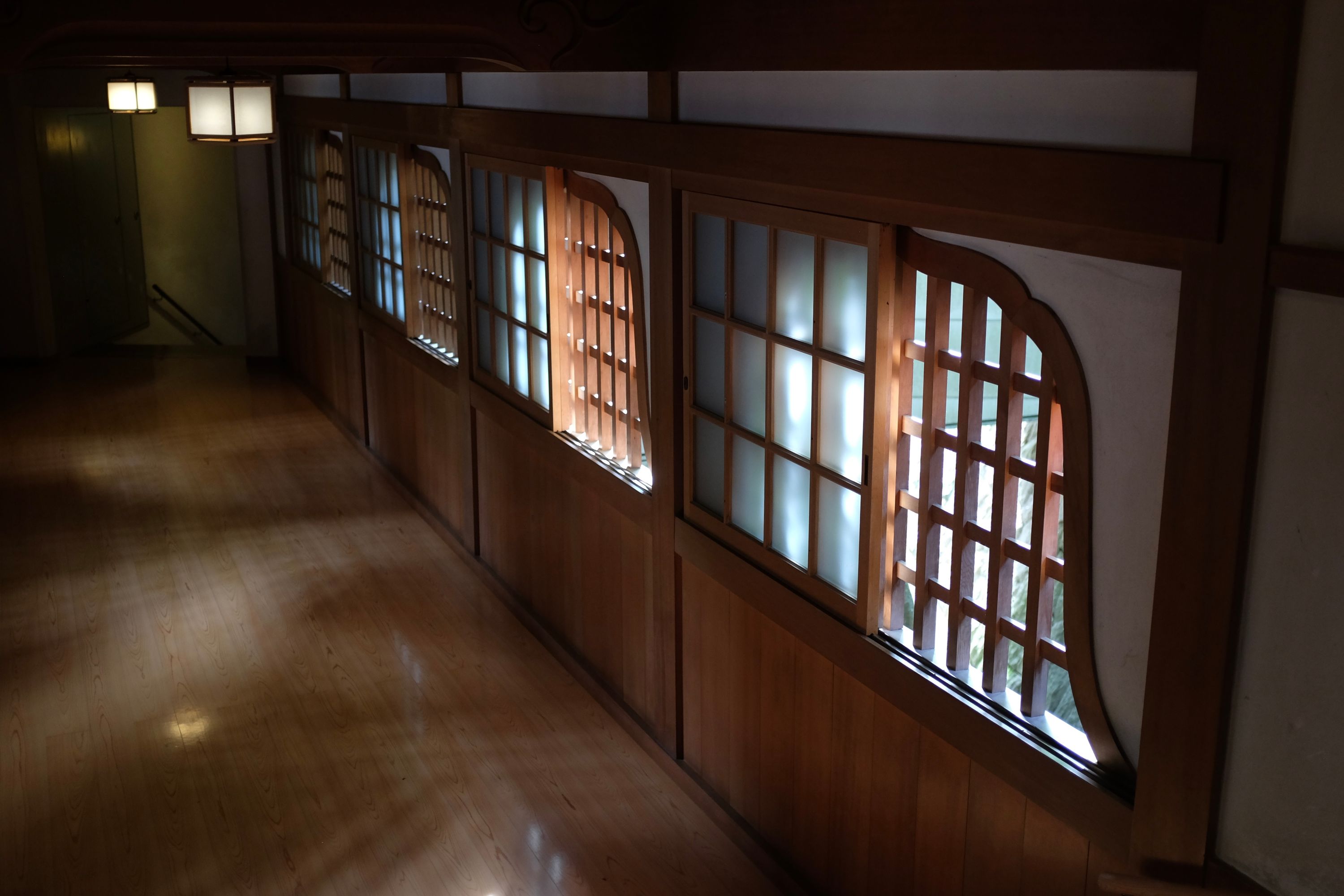 Carved wooden windows direct light on a polished wooden floor.