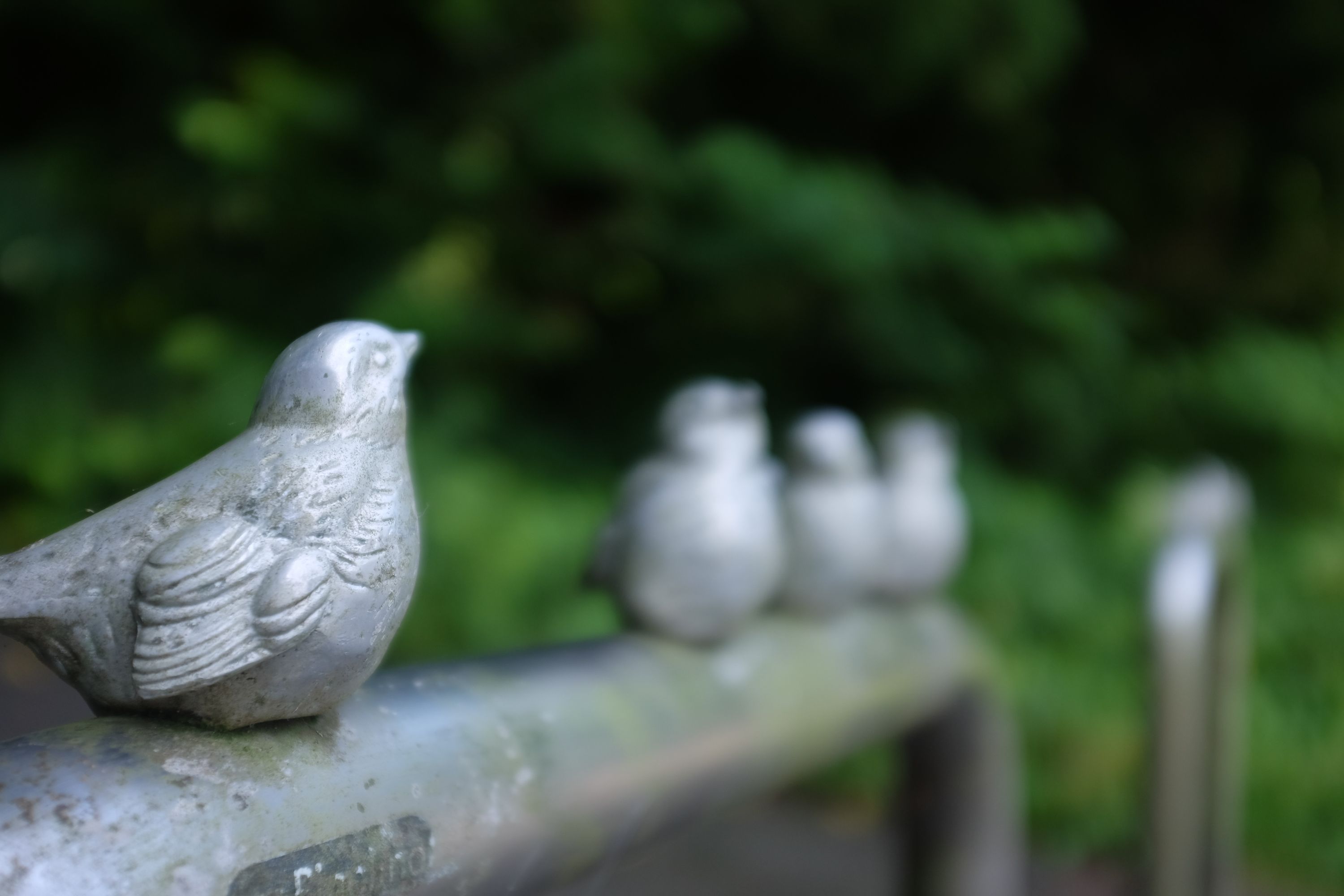 Small metal figures of sparrow line a guardrail.