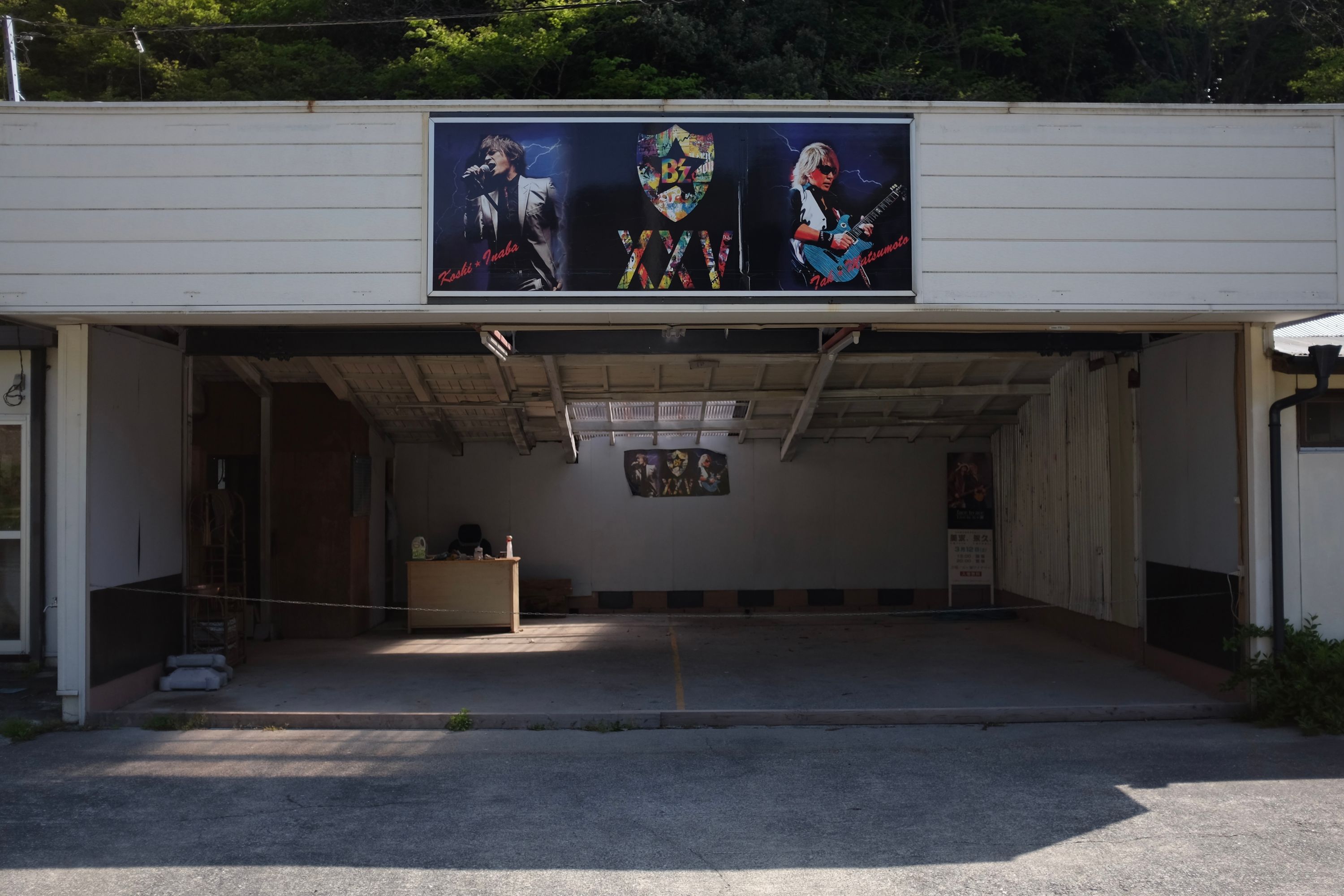 An empty garage with a triptych of power metal posters above its entrance, replicated on the back wall.