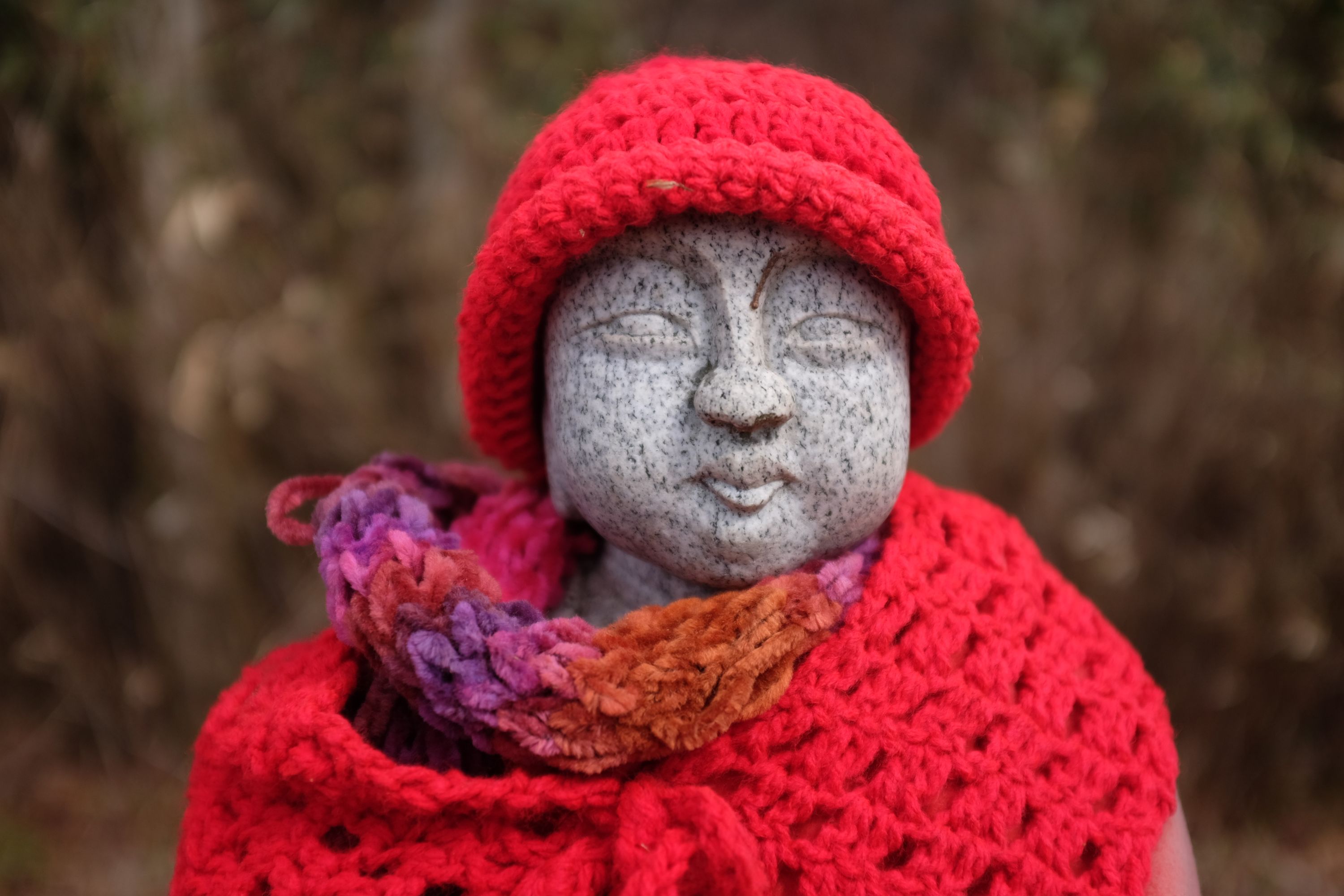 Portrait of the statue, who wears a red knit cap and a red scarf.