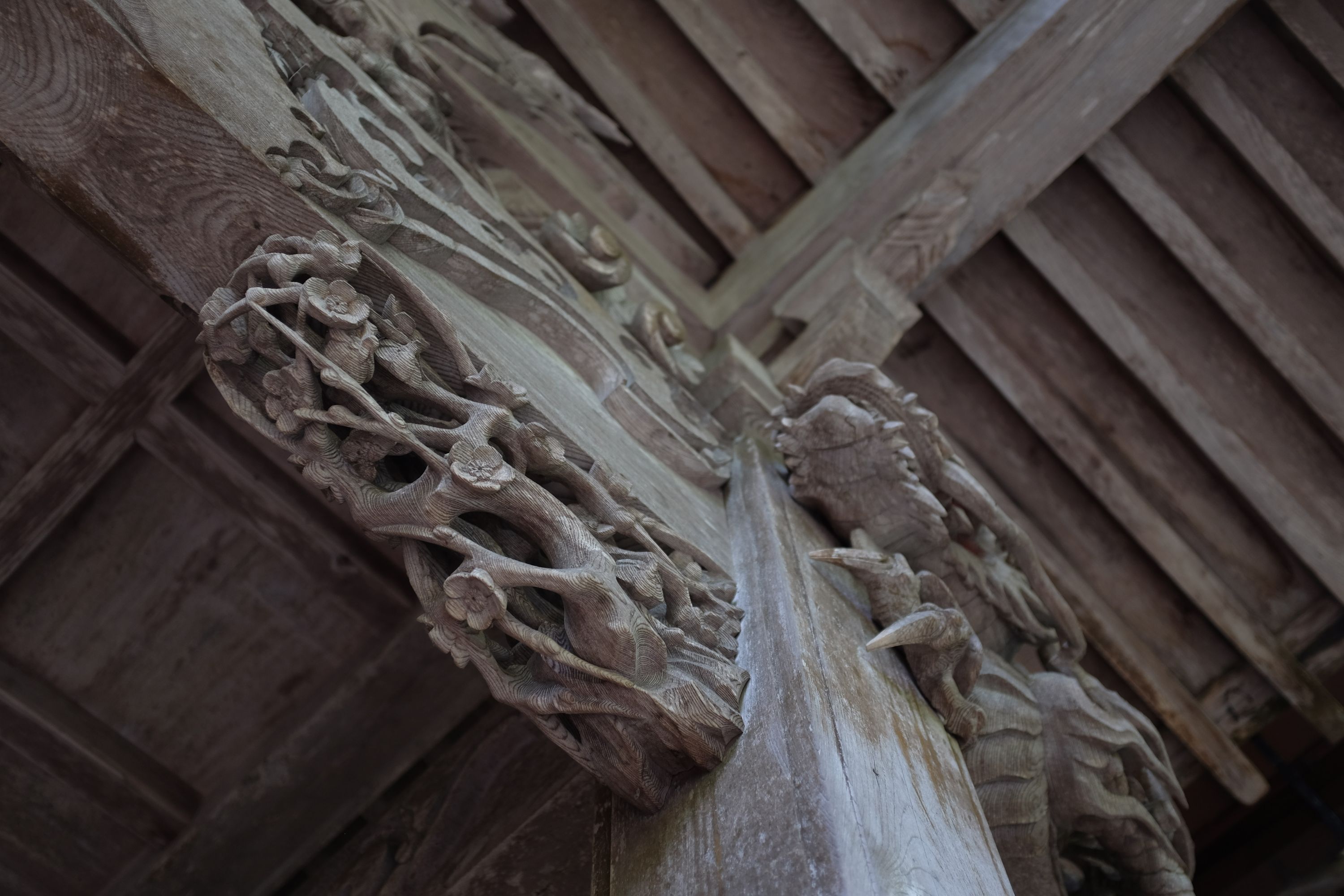 Carved wooden flowers and dragons on a column.