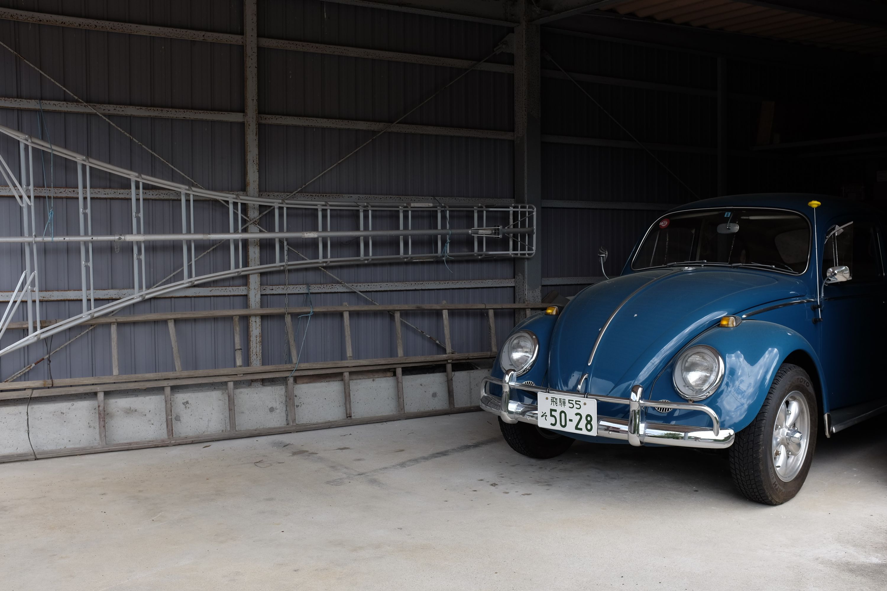 A petrol blue Volkswagen Beetle parked in a garage.