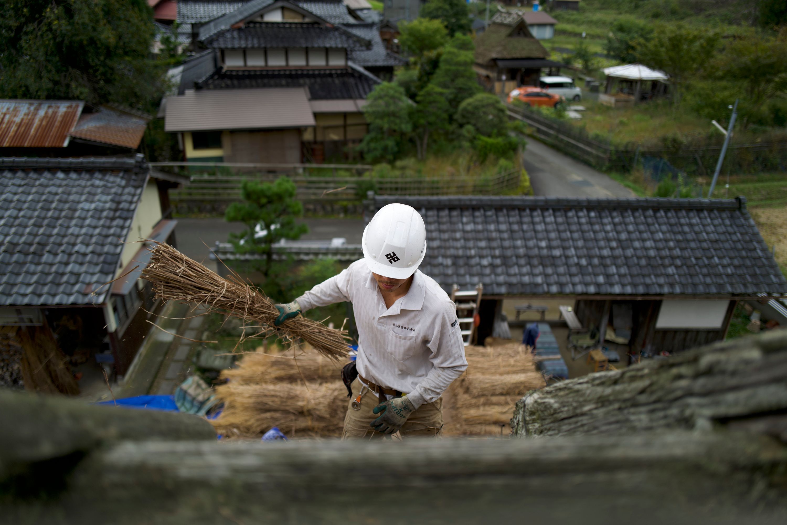 A thatcher works on the roof of a traditional Japanese house
