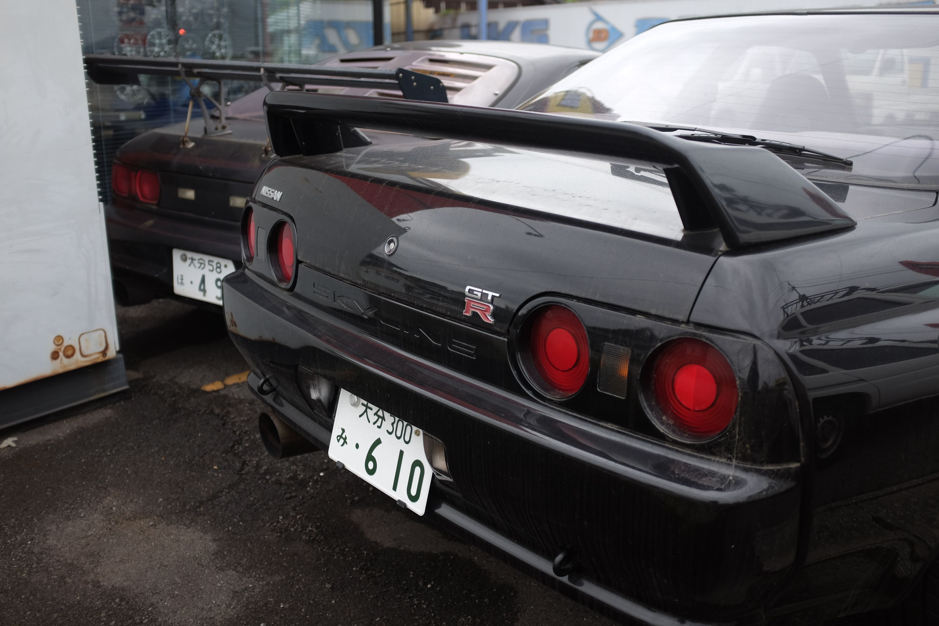 The rear ends of two black Nissan Skyline GT-R’s.