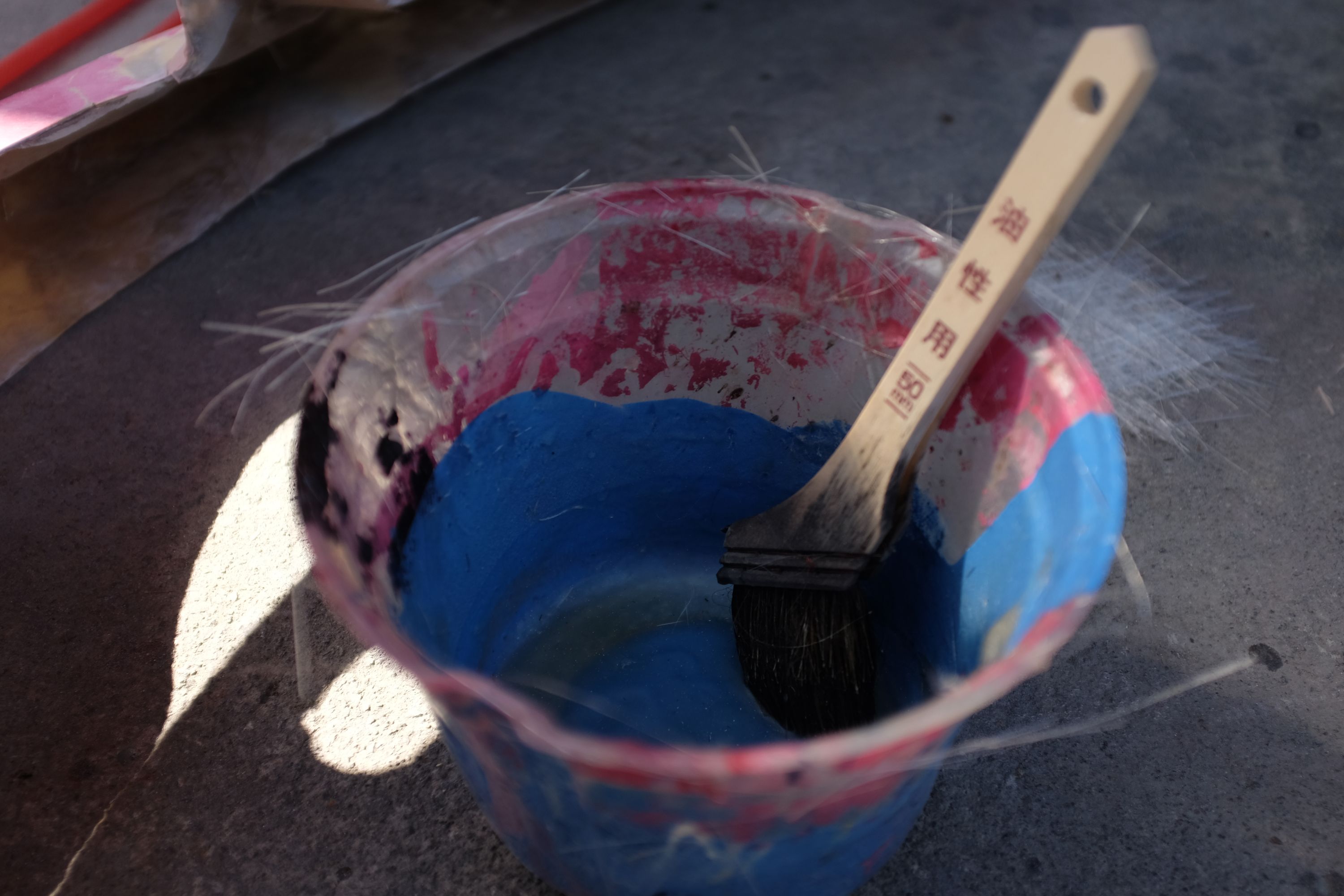 A bucket of sky blue paint with a brush inside.