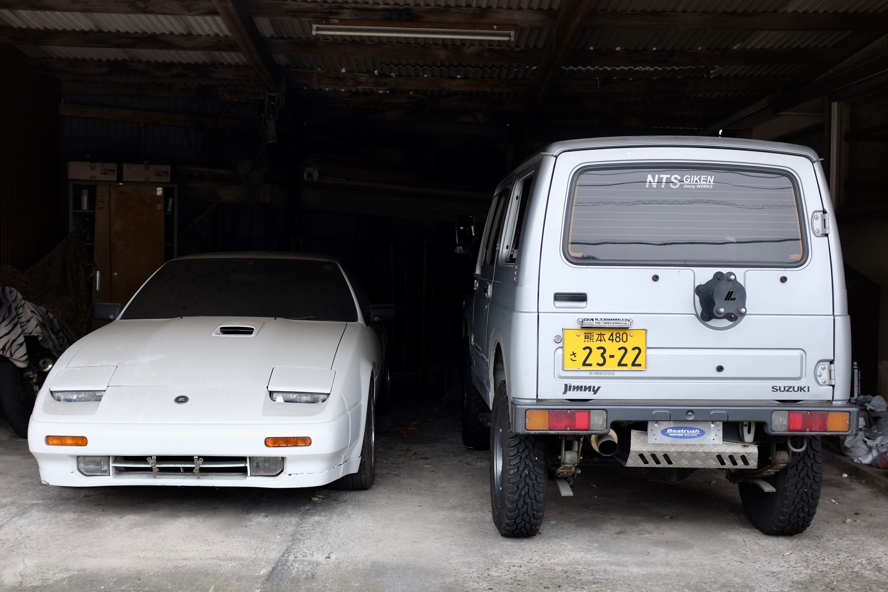 A Nissan Z and a Suzuki Jimny in a garage.