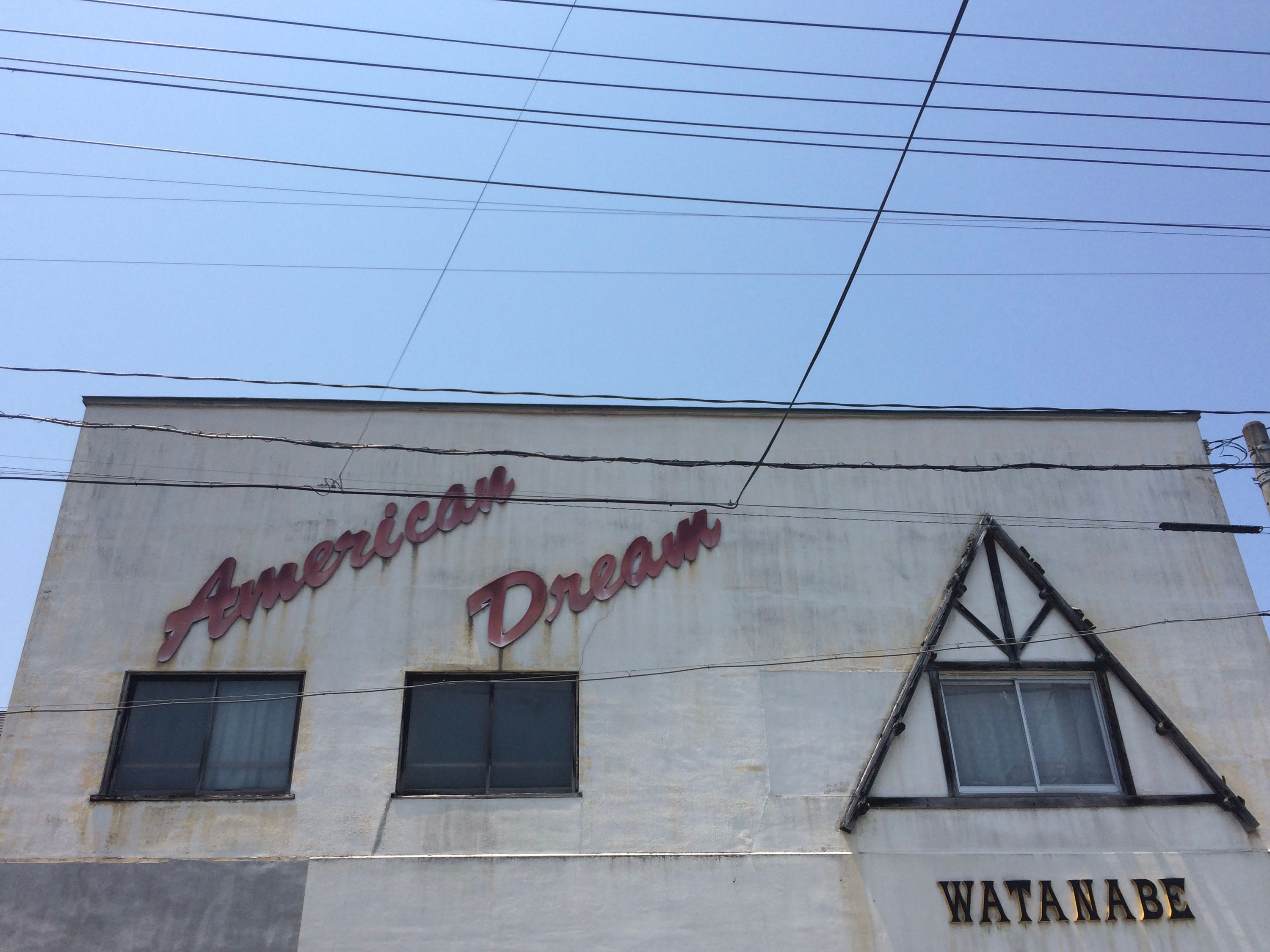 A building with a sign saying American Dream in red cursive letters, and another saying Watanabe in block capitals.