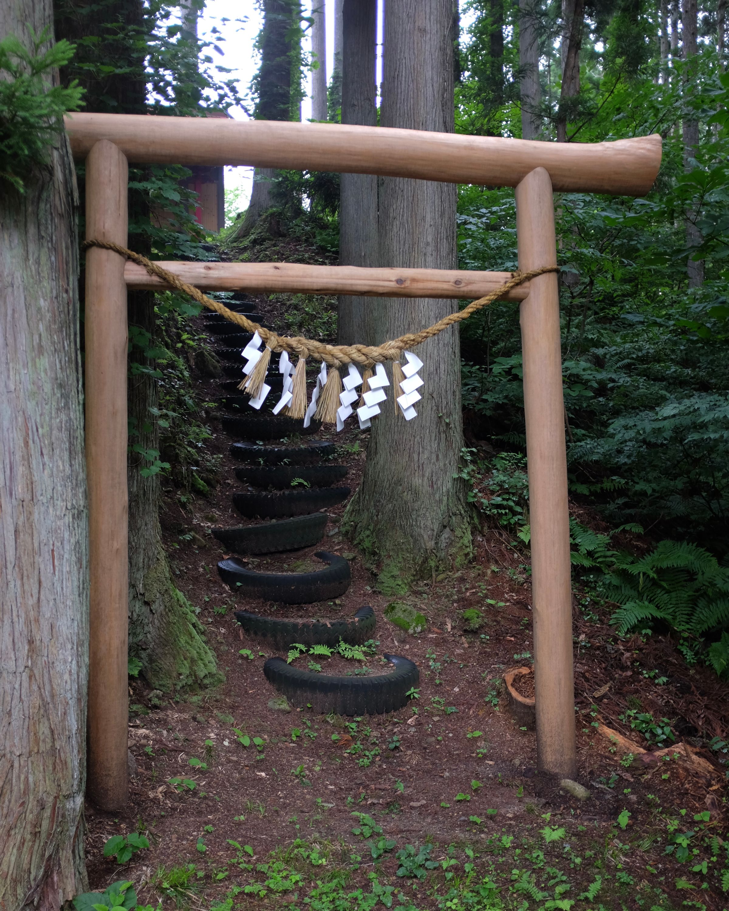 Steps made of car tyres lead up a hill from the gate of a shrine.