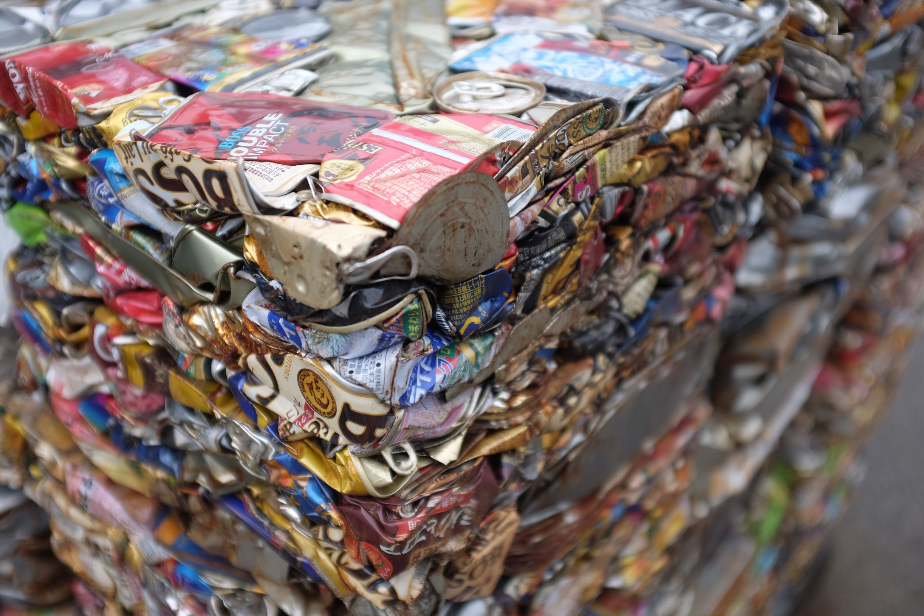 A large cube made of crushed coffee cans at a recycling plant.