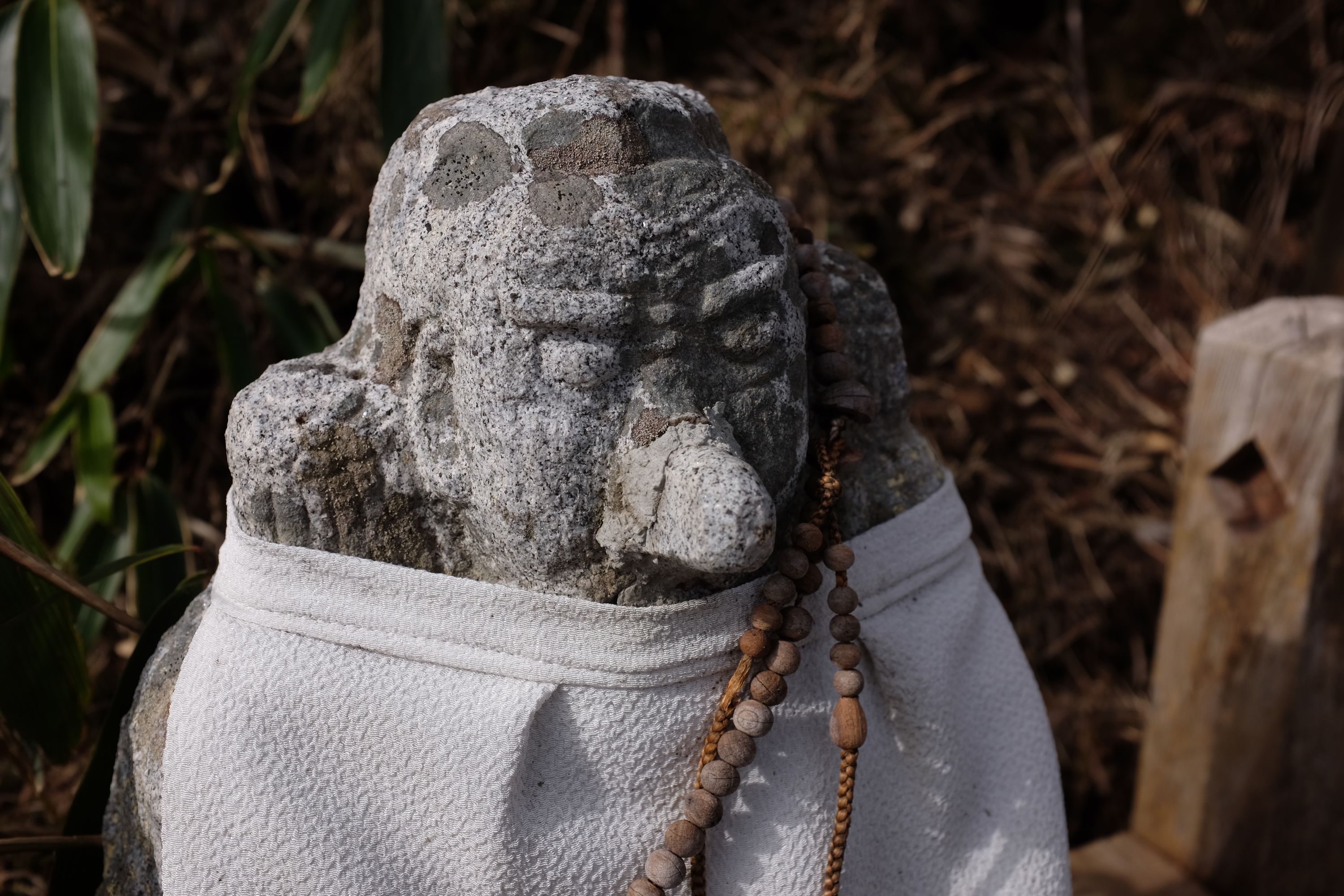 A small statue of a mountain deity with a huge nose and bulging eyes wears a white apron and a necklace of beads.