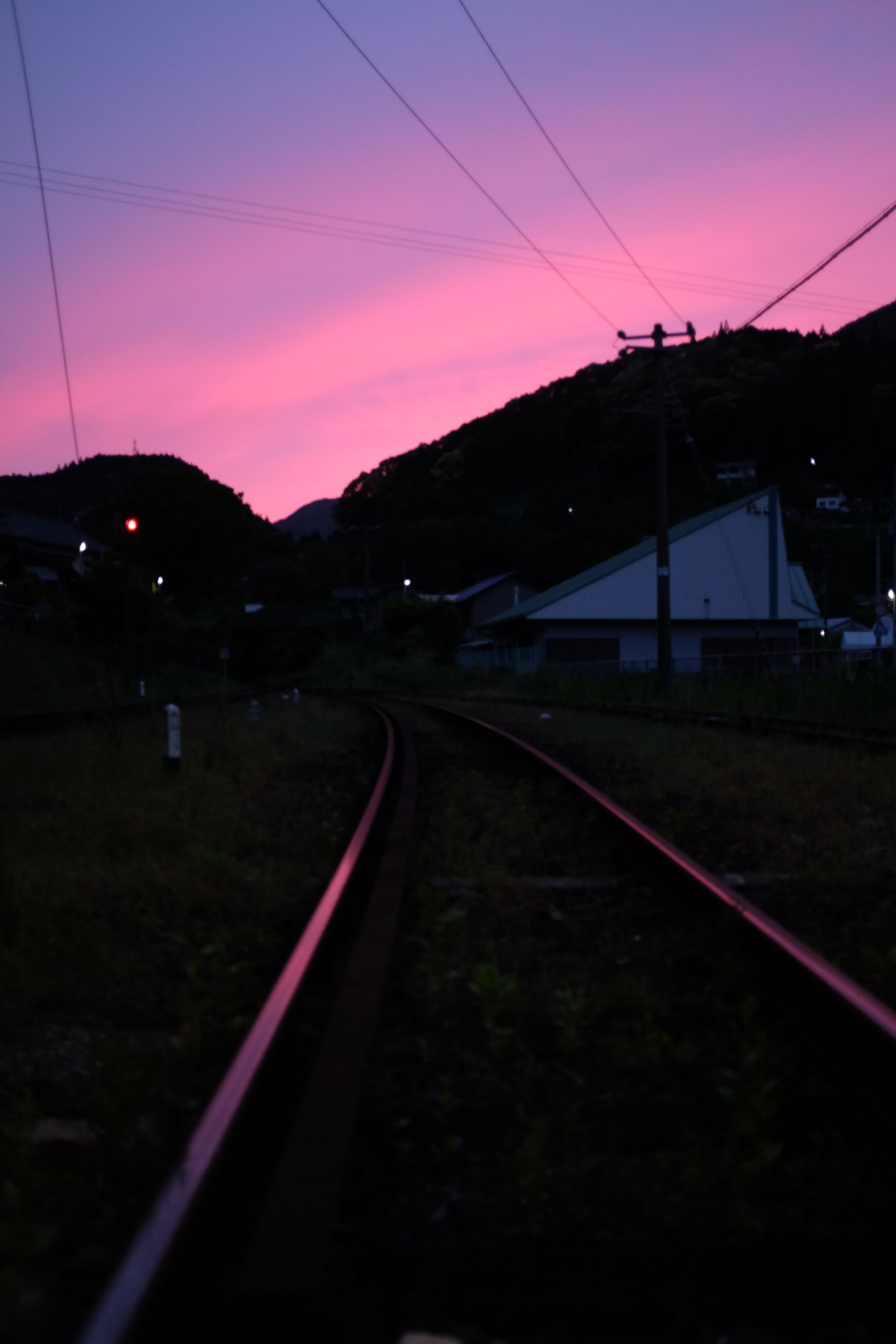Looking at a blue-pink-purple sunset from the middle of a pair of railway tracks.