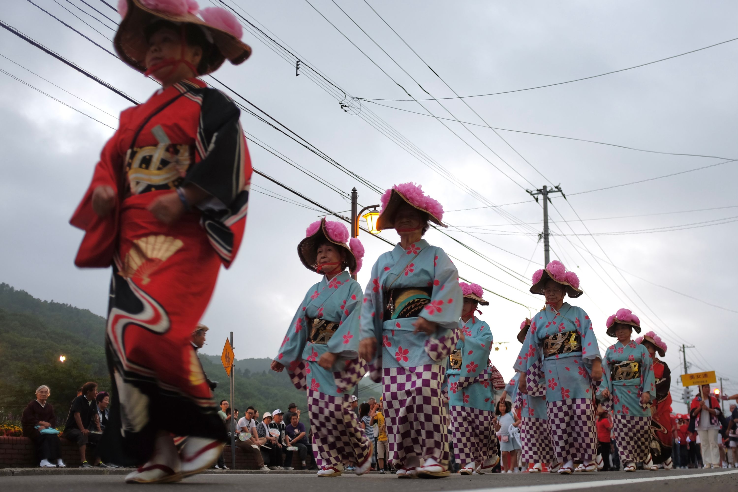 A group of elderly women wearing festival kimonos walk in procession.