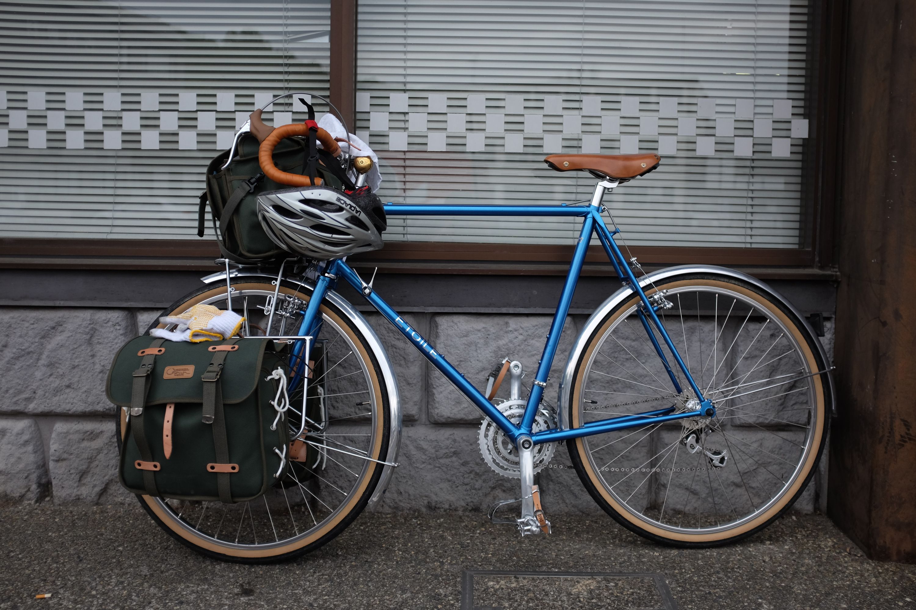 A beautiful blue touring bicycle with green canvas luggage.