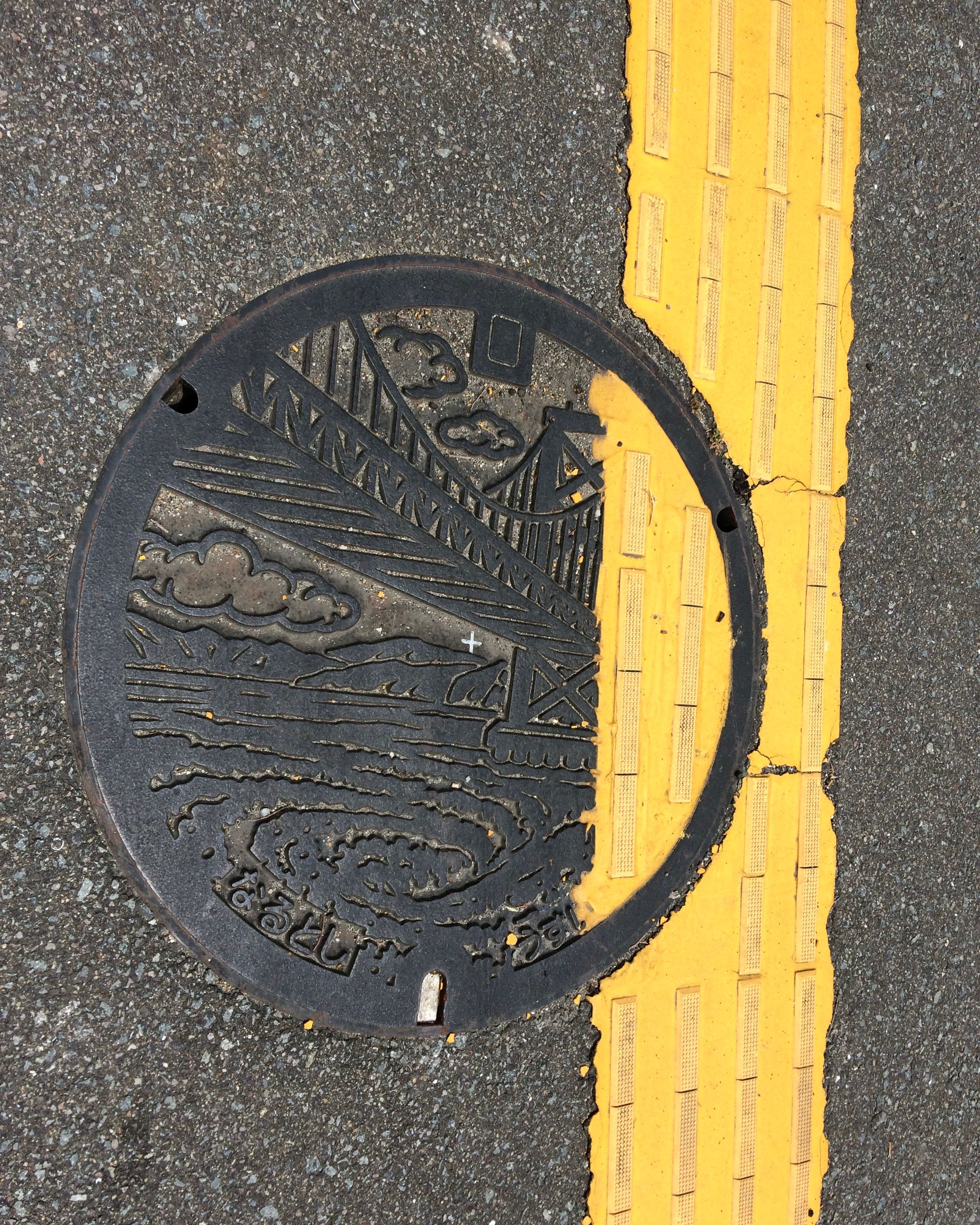 Manhole cover with the Great Naruto Bridge and the Naruto Whirlpools on it.