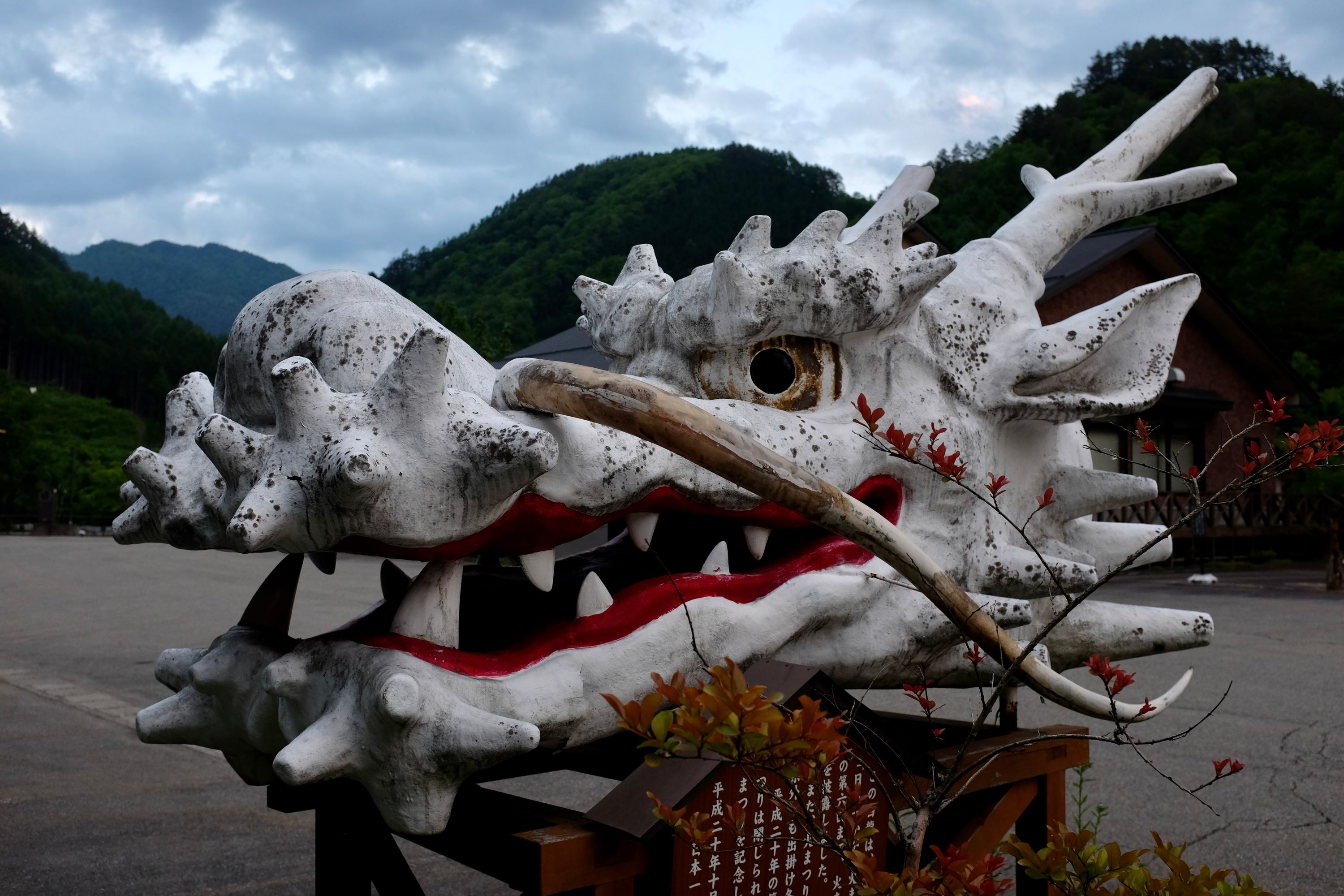 The head of a white, Japanese-style dragon on a plinth by the road.