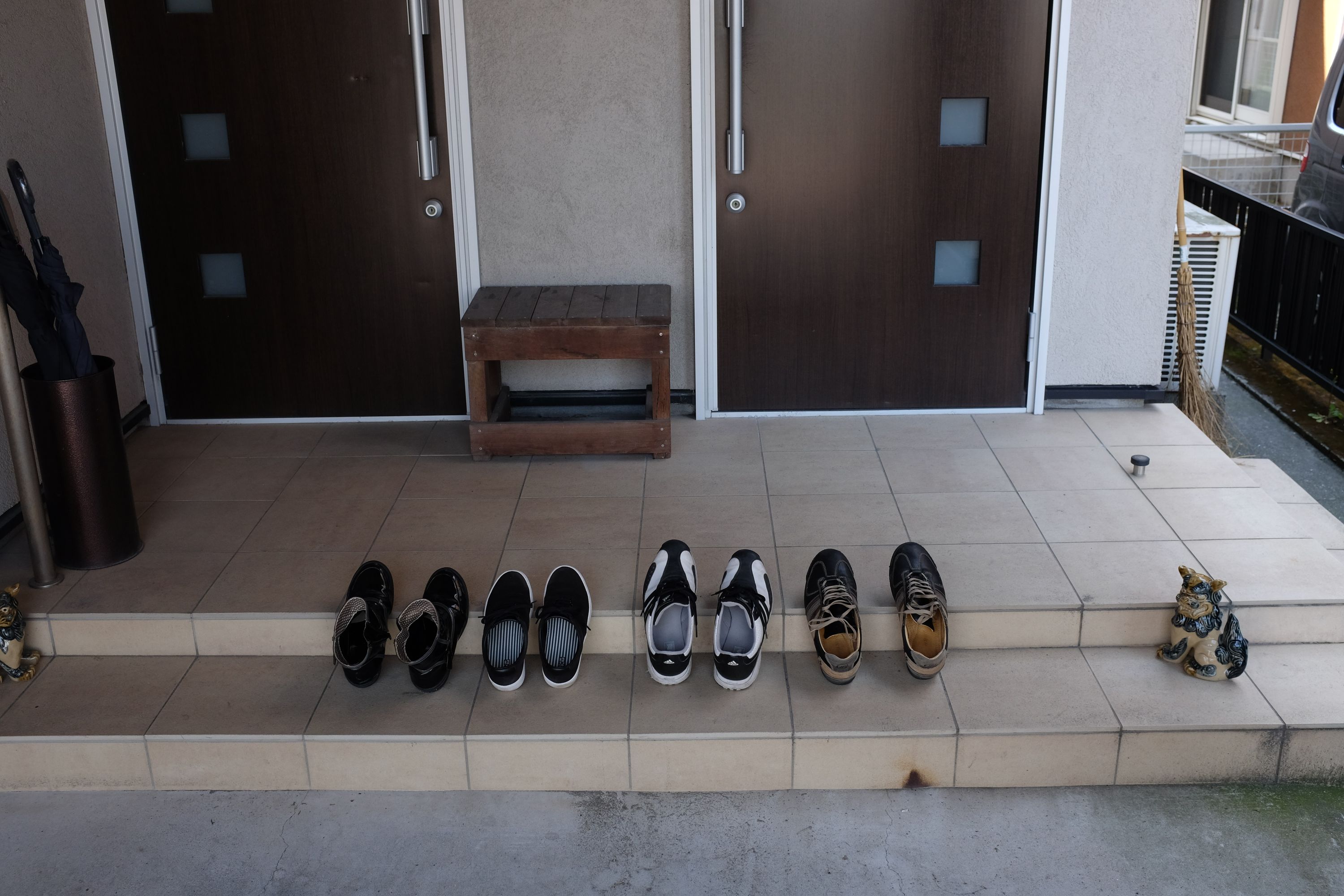 Four pairs of shoes on the porch of a house.