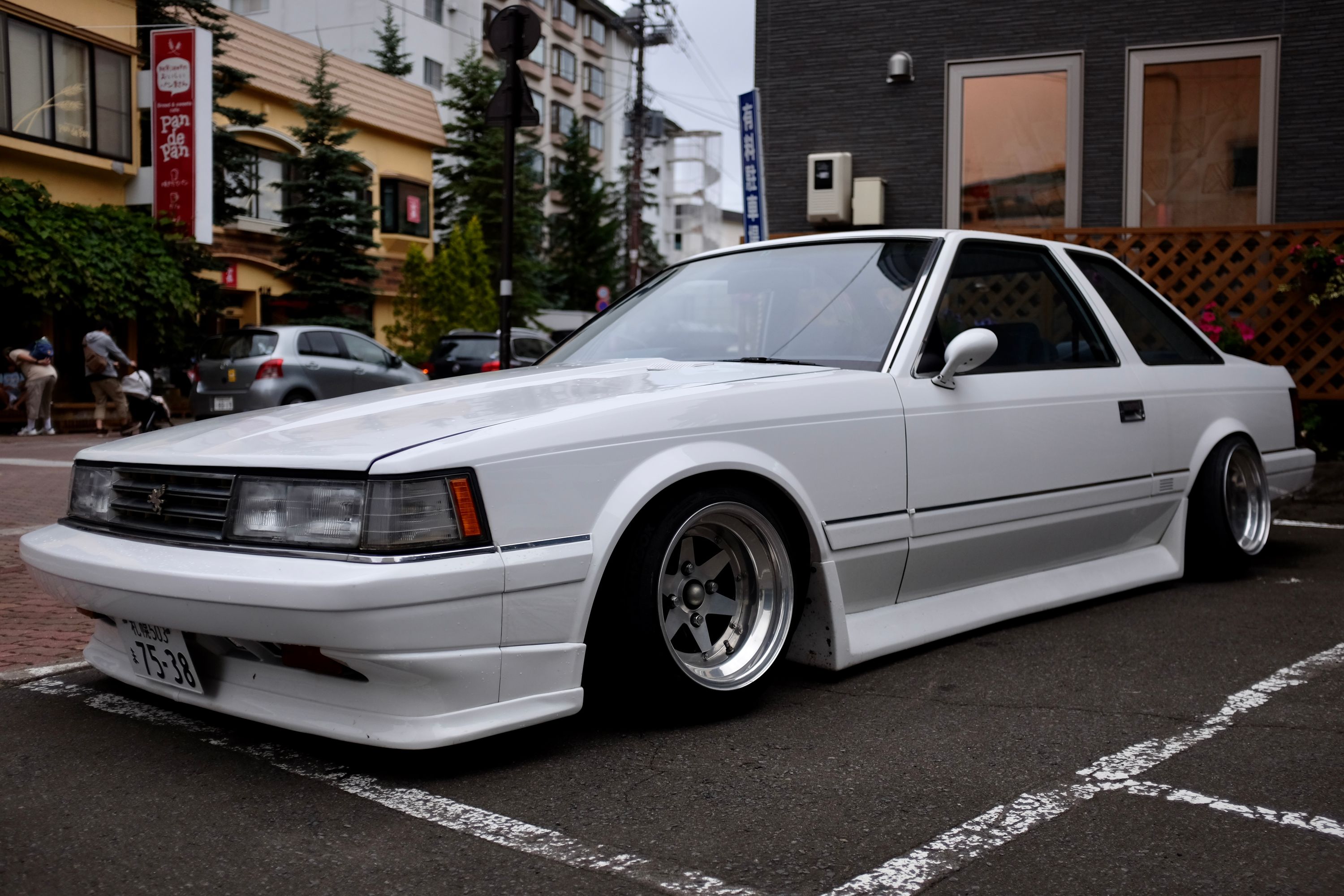 An extremely low-slung angular white Japanese sports car in a parking lot.