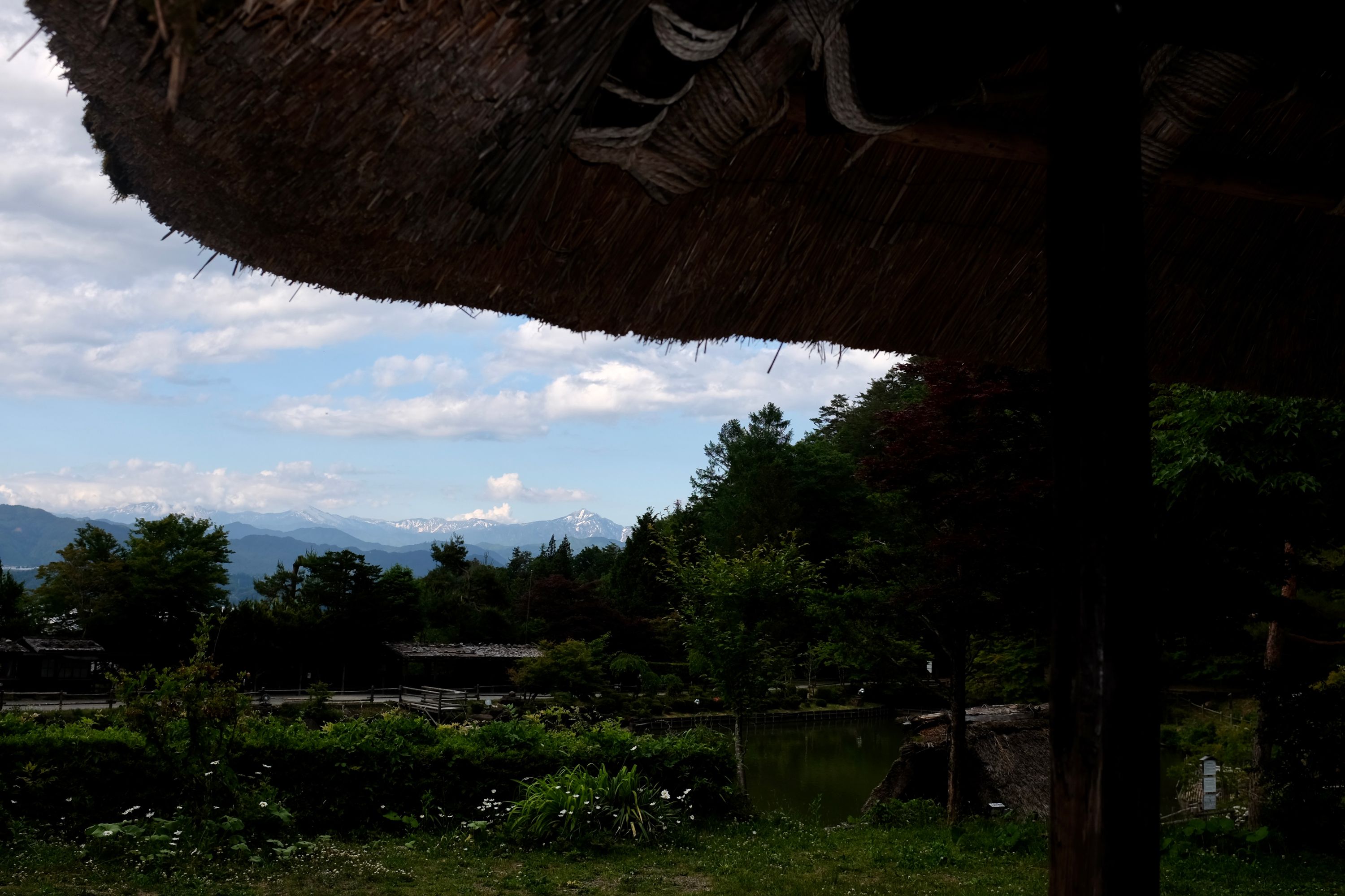Looking out on the Hida Mountains from underneath the eaves of a thatch-roofed Japanese farmhouse.
