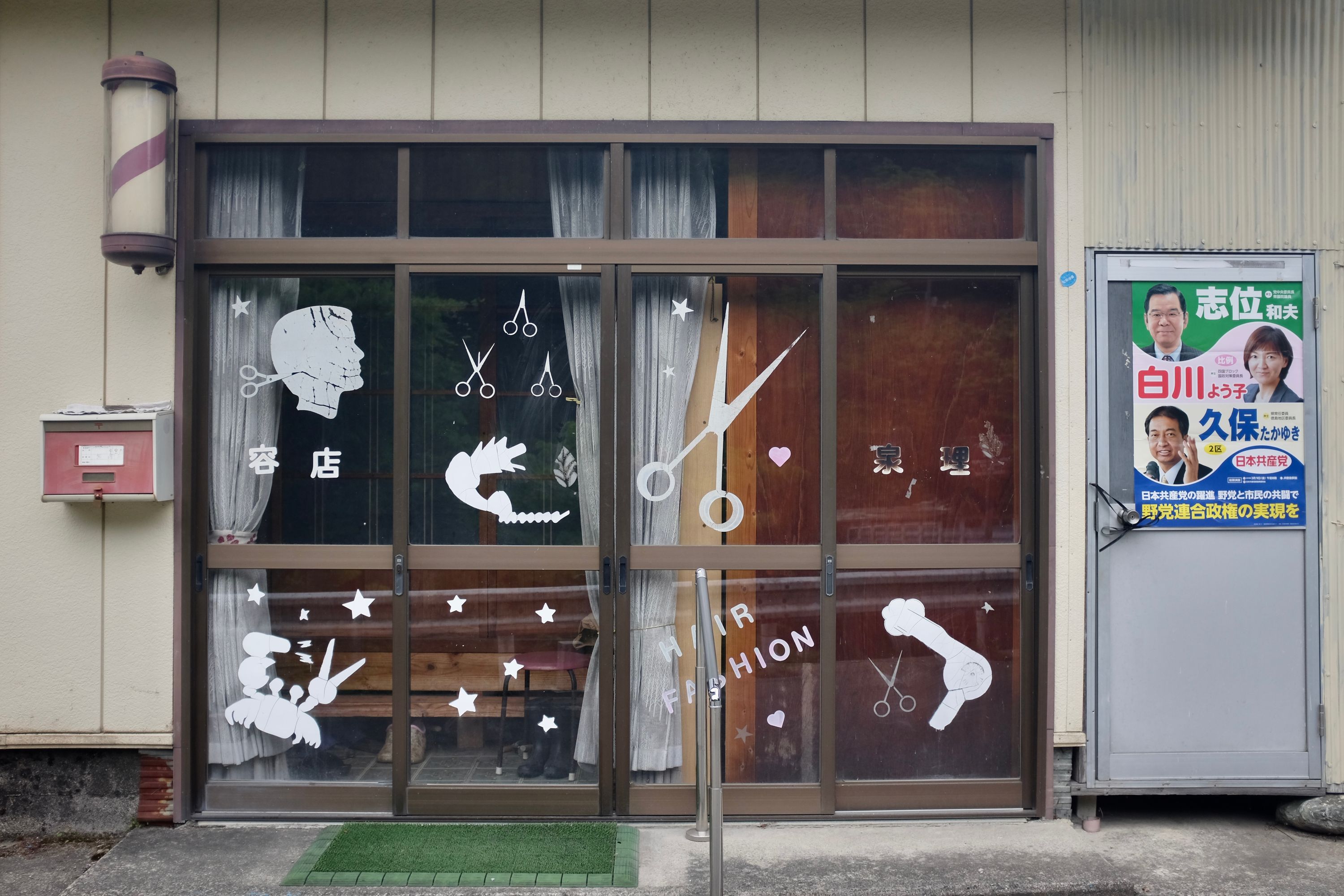 The door of a barbershop with a stencil of a small land crab, its pincers modified into a blow-dryer and a pair of scissors.