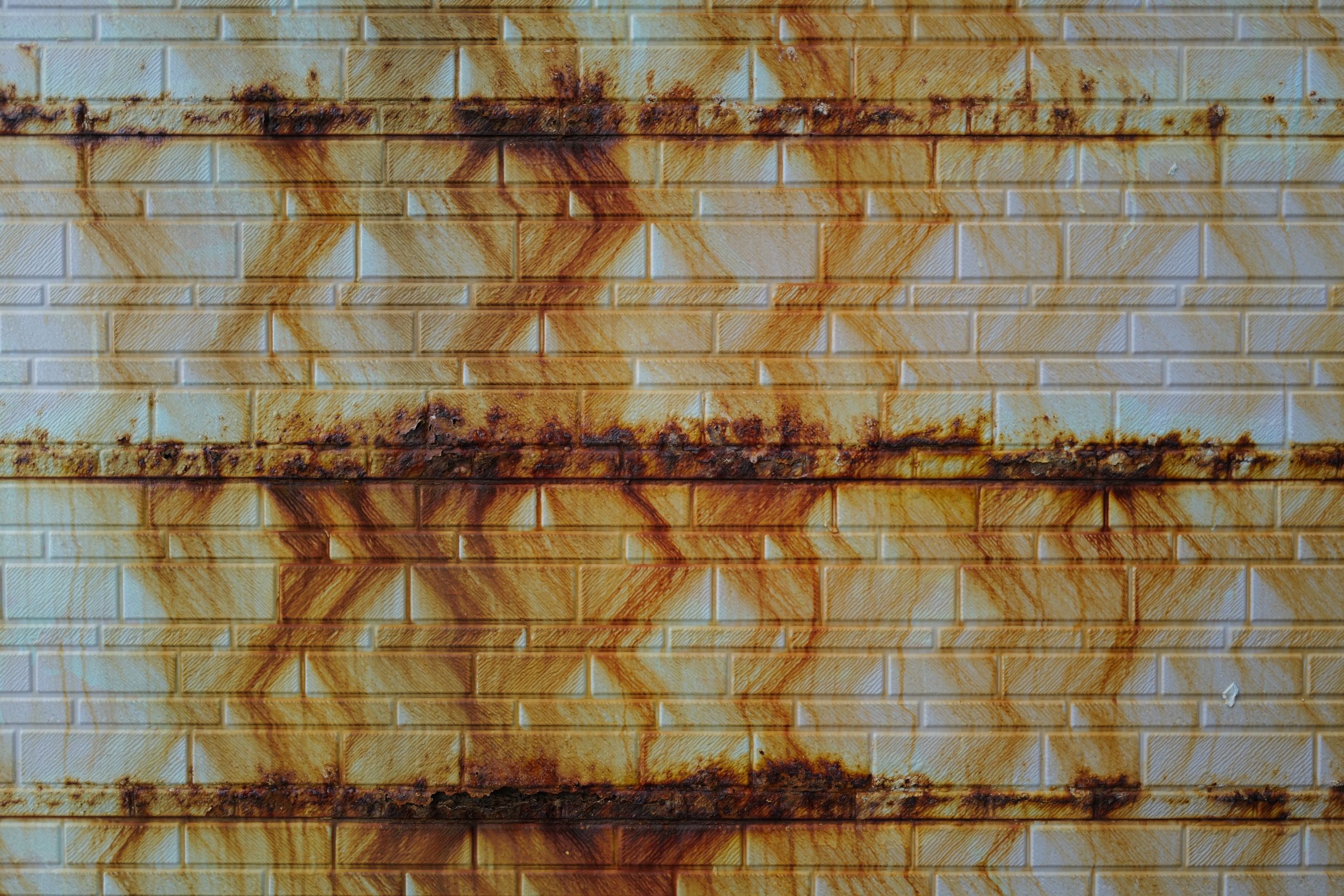 Rust streaks down the side of a building in wavy patterns