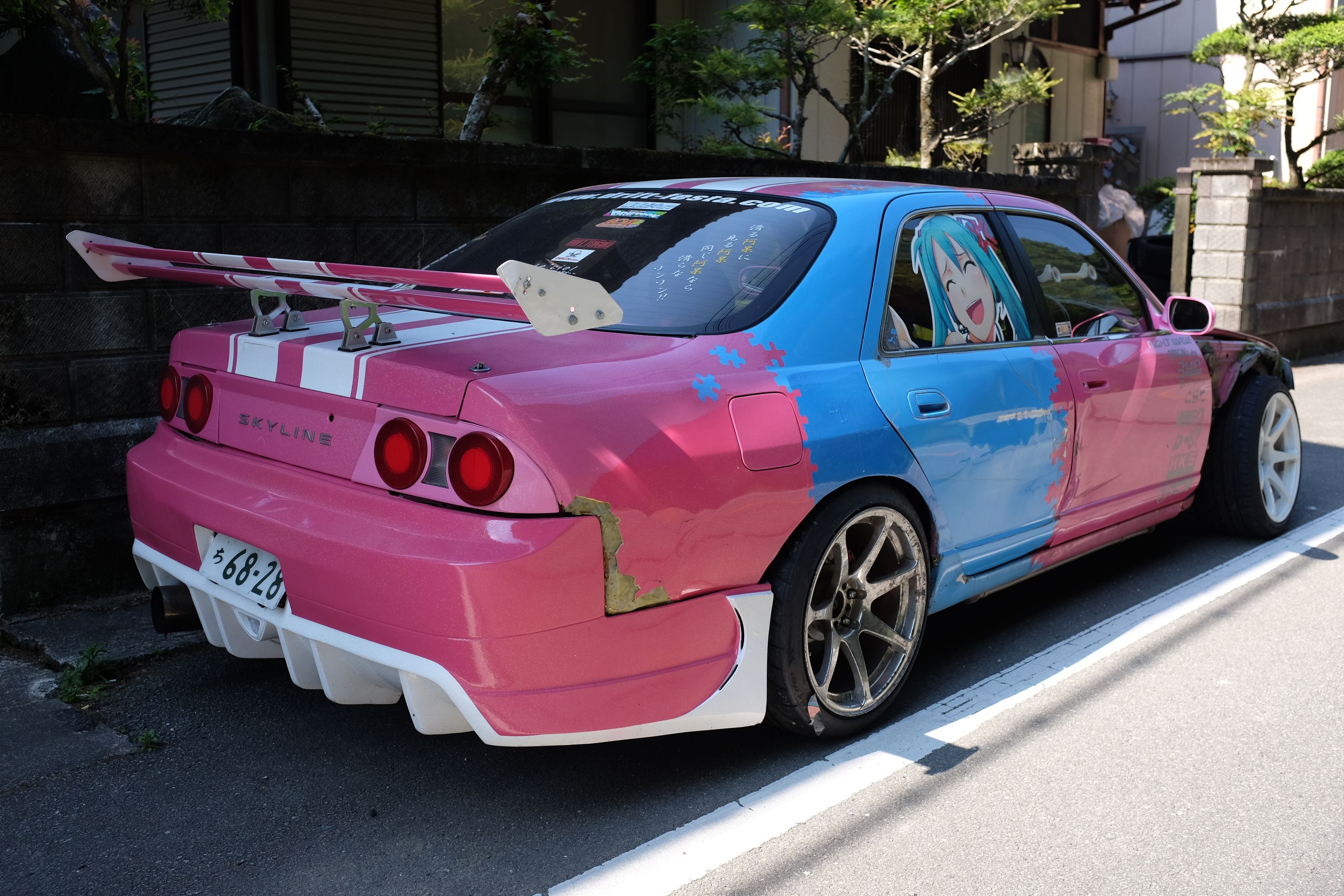 The pink rear end of the car has a huge aftermarket wing.