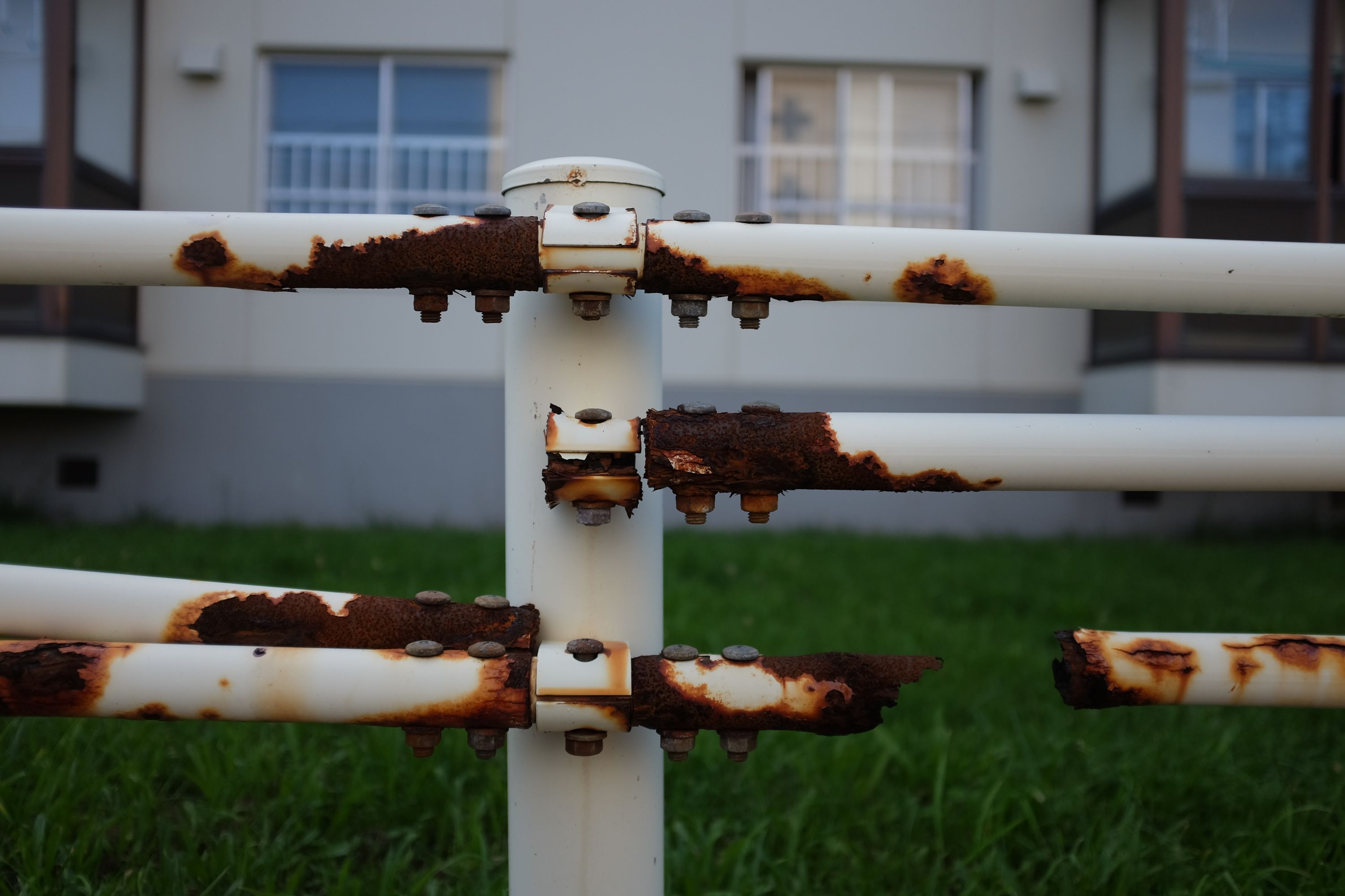 A white railing completely rusted through in places.