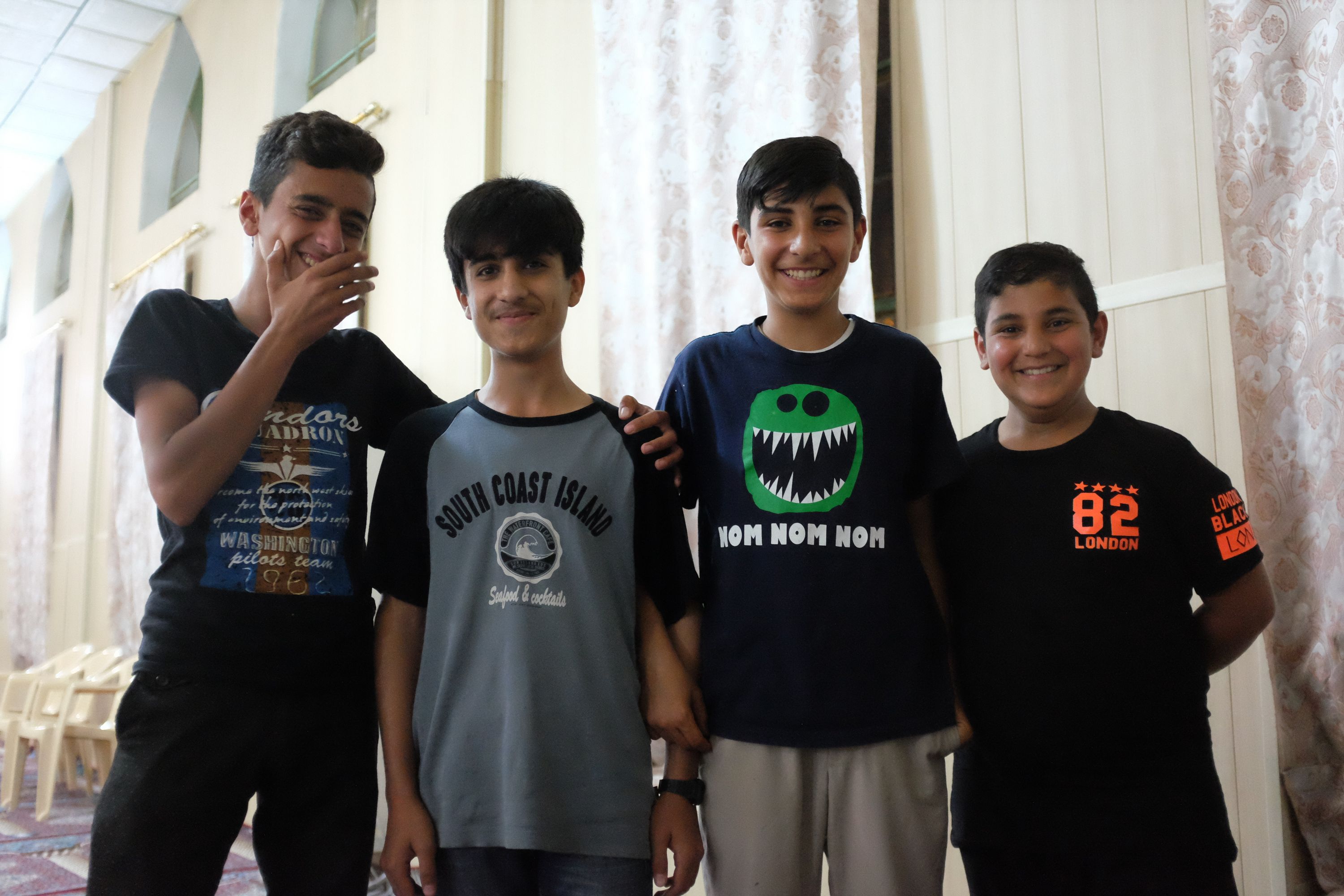 Four boys stand in a line and smile into the camera.