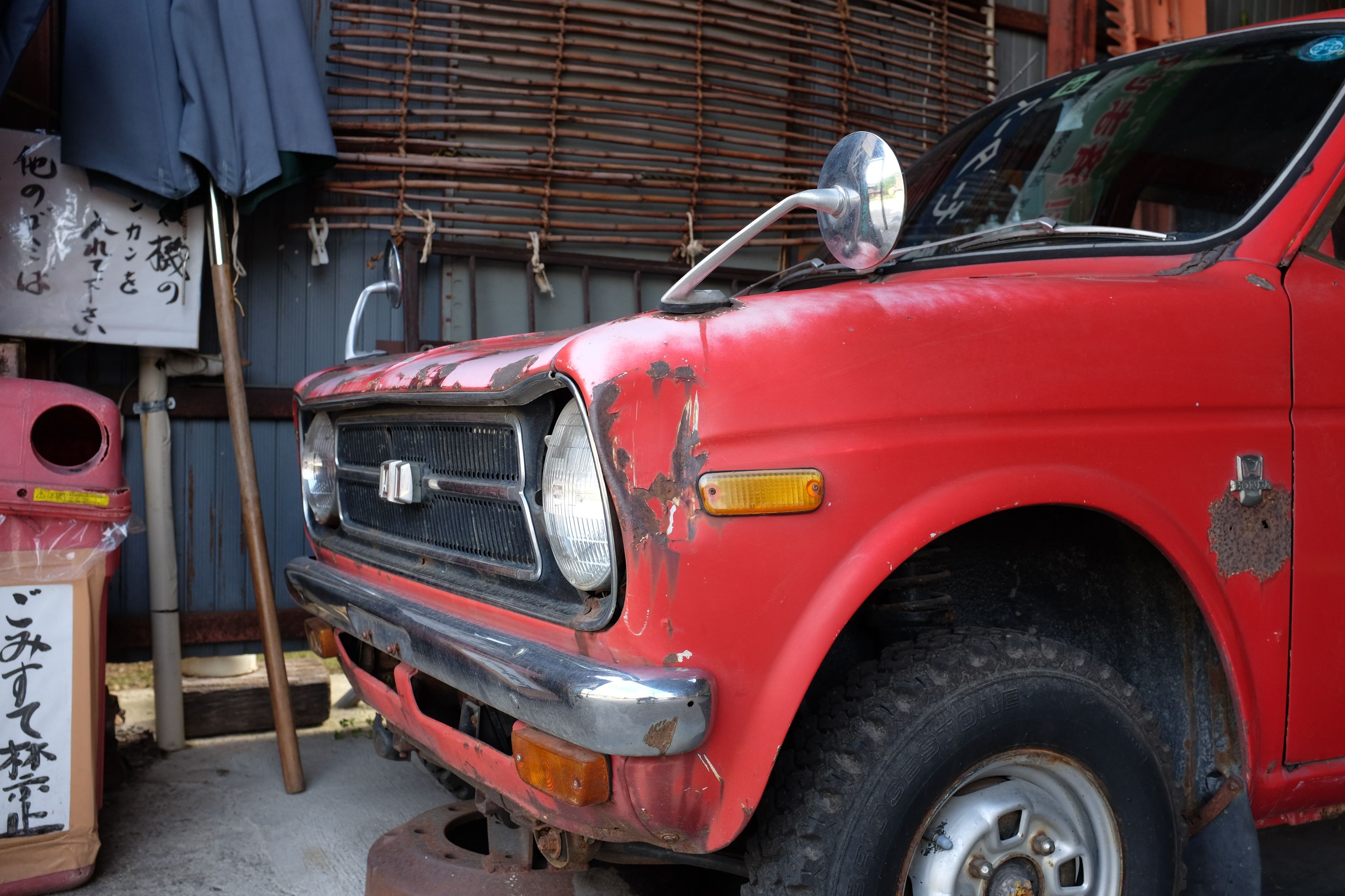 A very old red Honda hatchback in a garage.