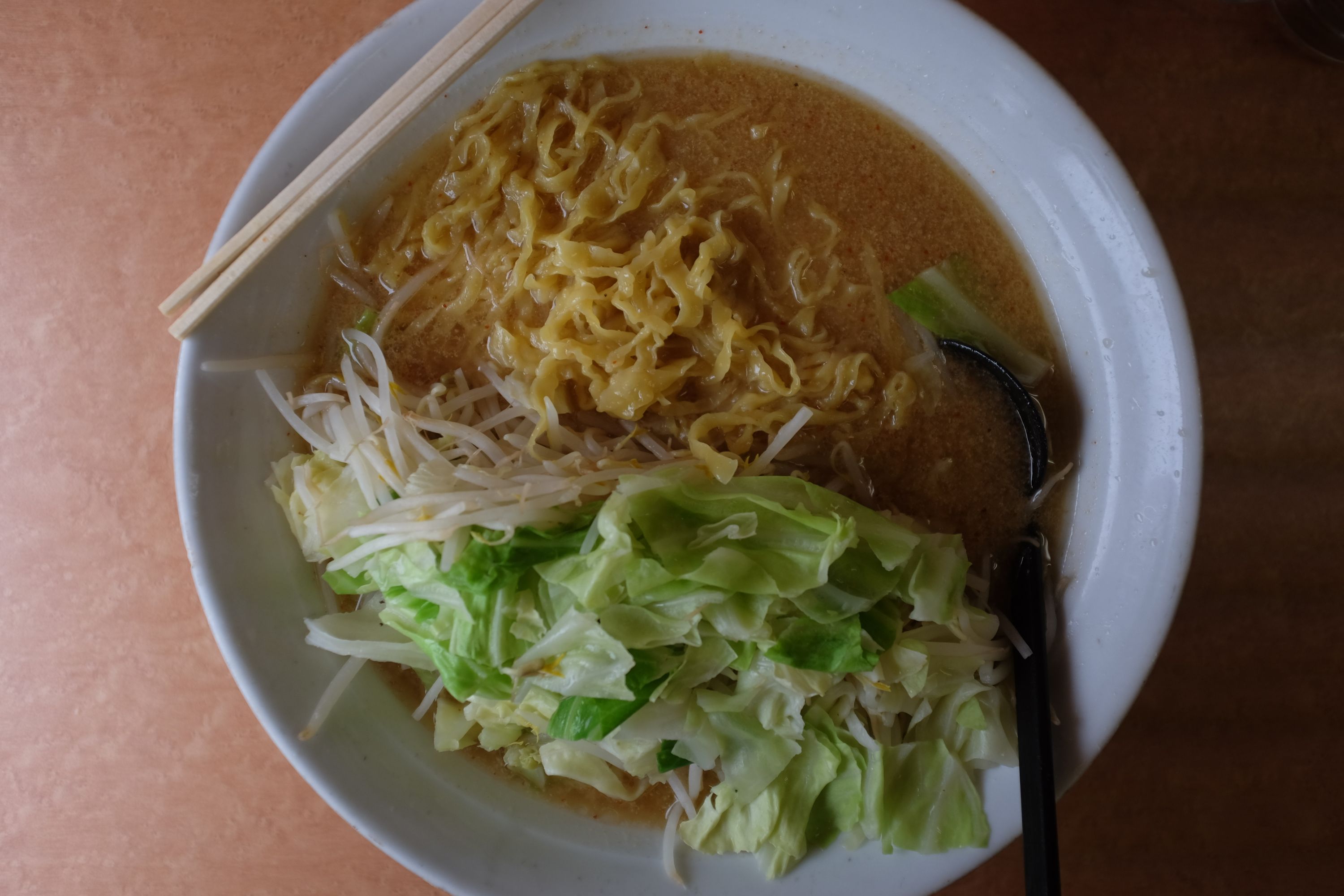 An enormous bowl of miso ramen makes a pair of chopsticks look like a child’s toy.