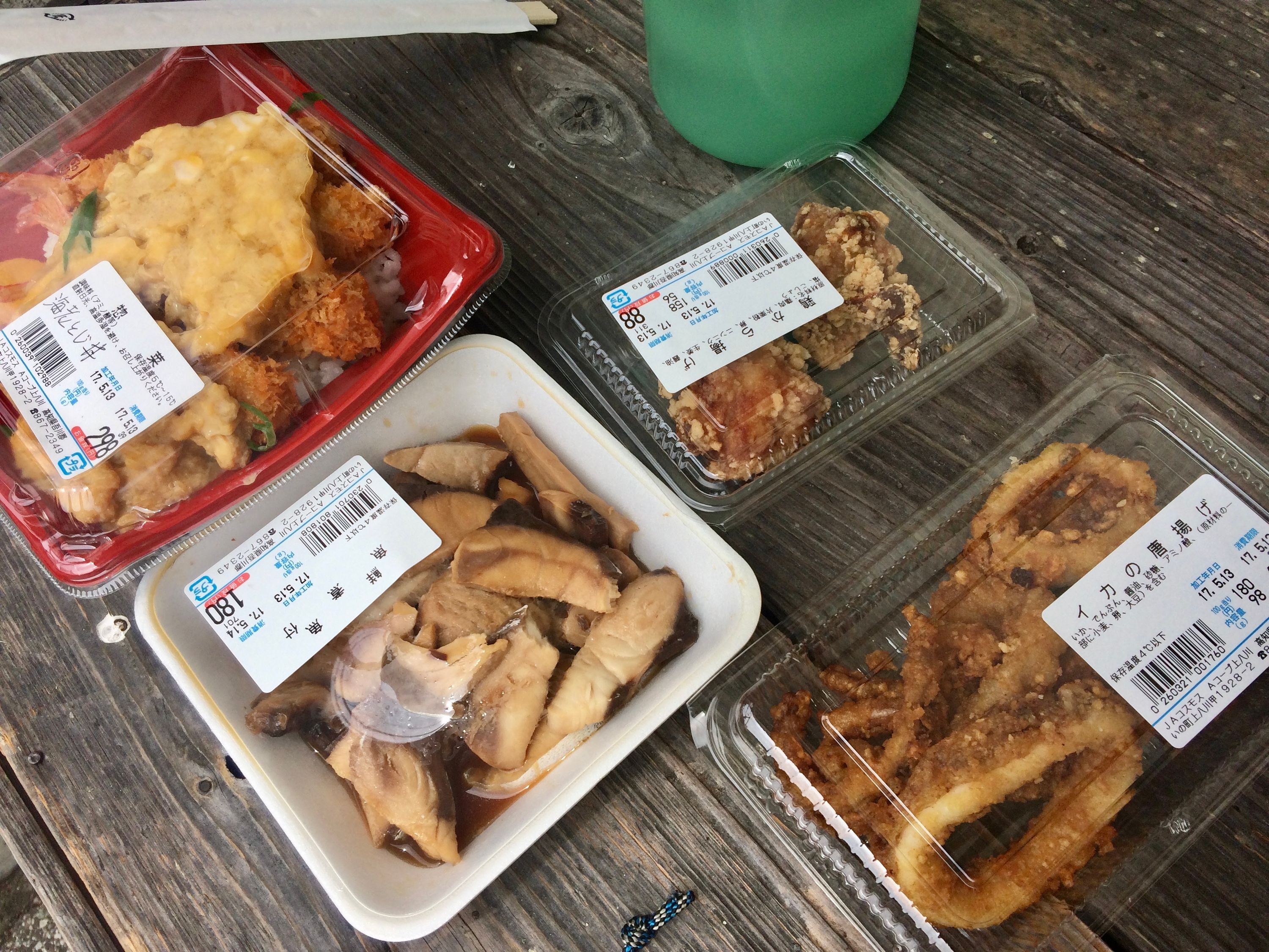 Several plastic boxes of fried convenience food store laid out on a bench, with a water bottle visible in the background.
