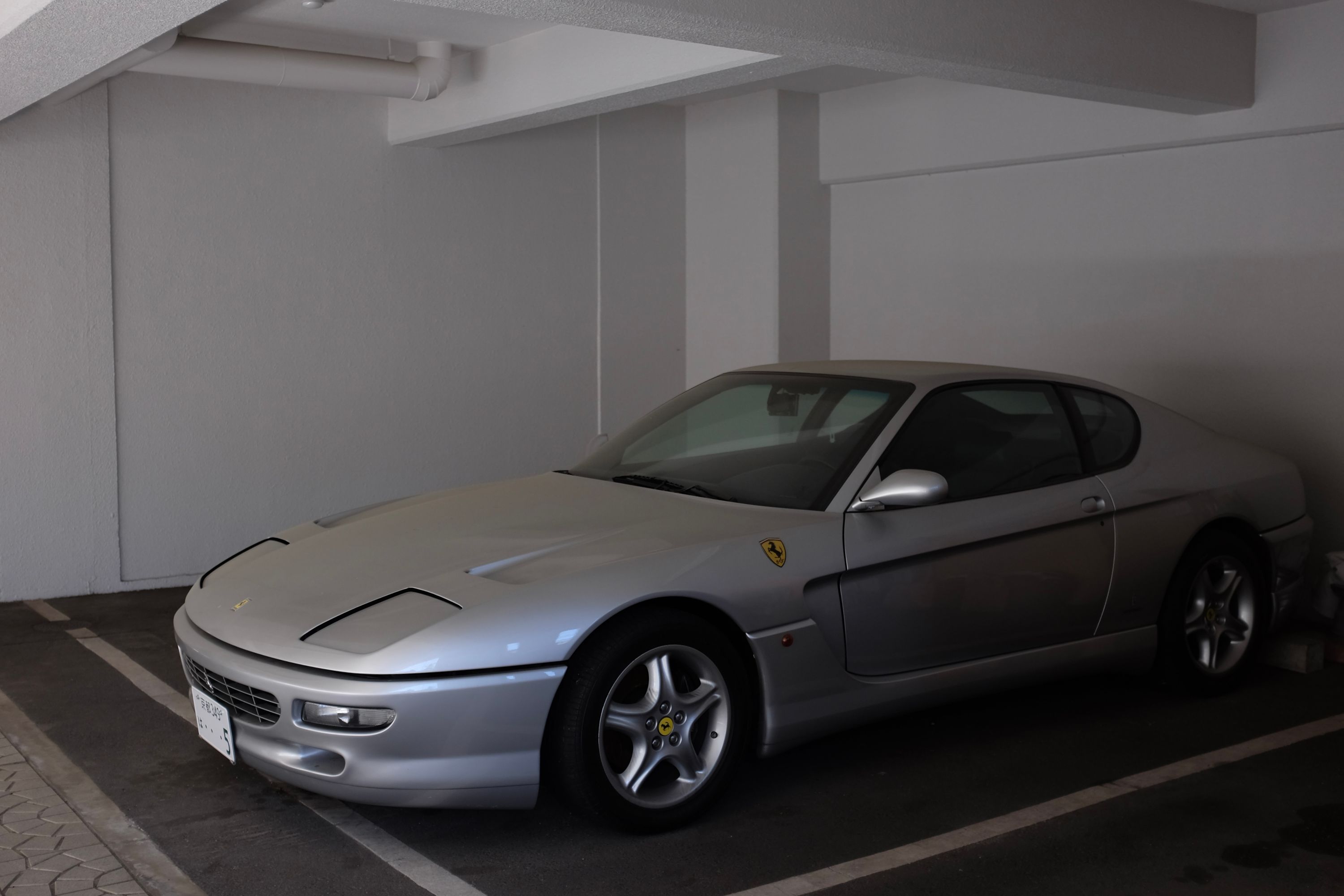A silver Ferrari 456 in a garage.