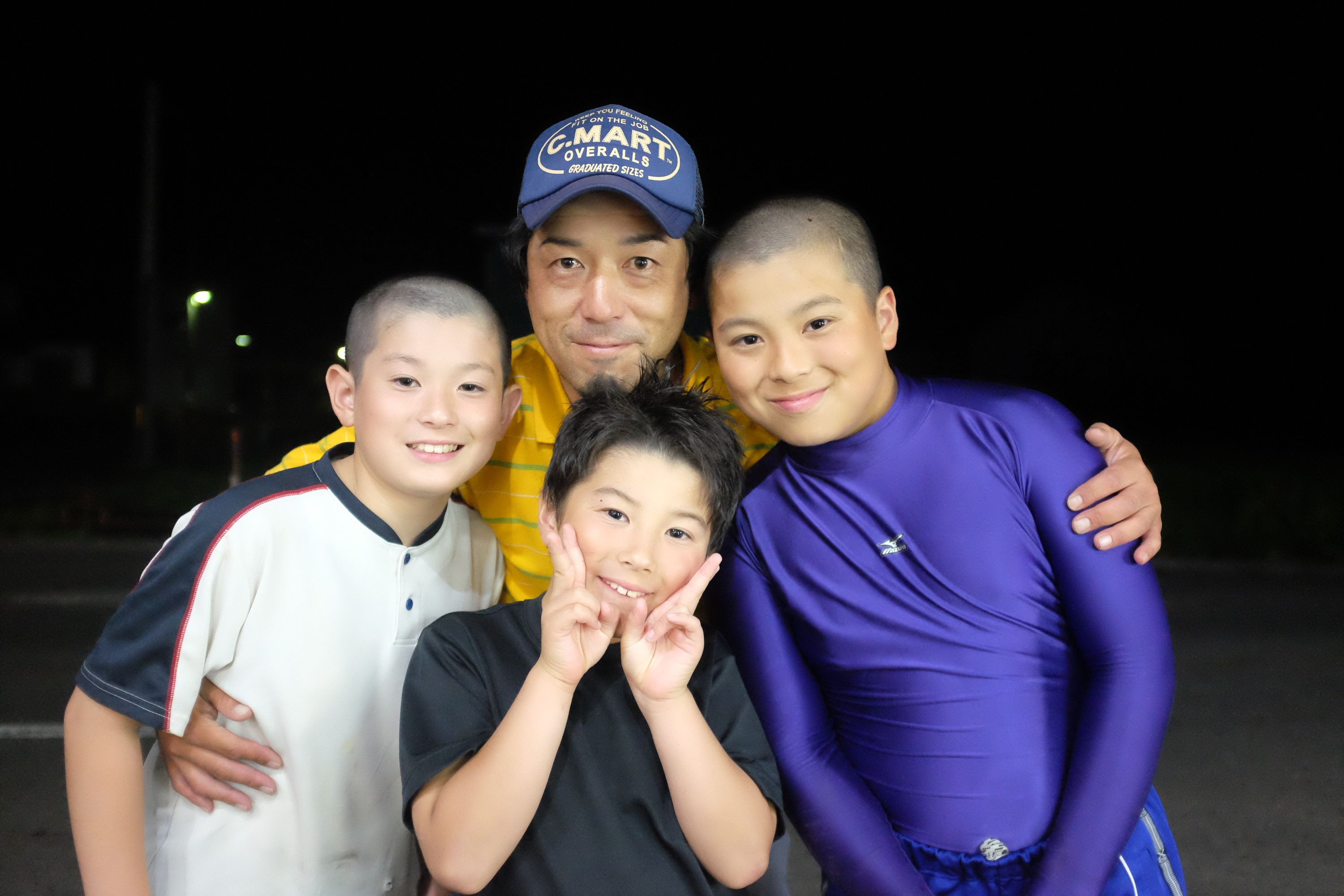 A Japanese man, Mr. Takamori, poses for the camera in the night with his three sons.