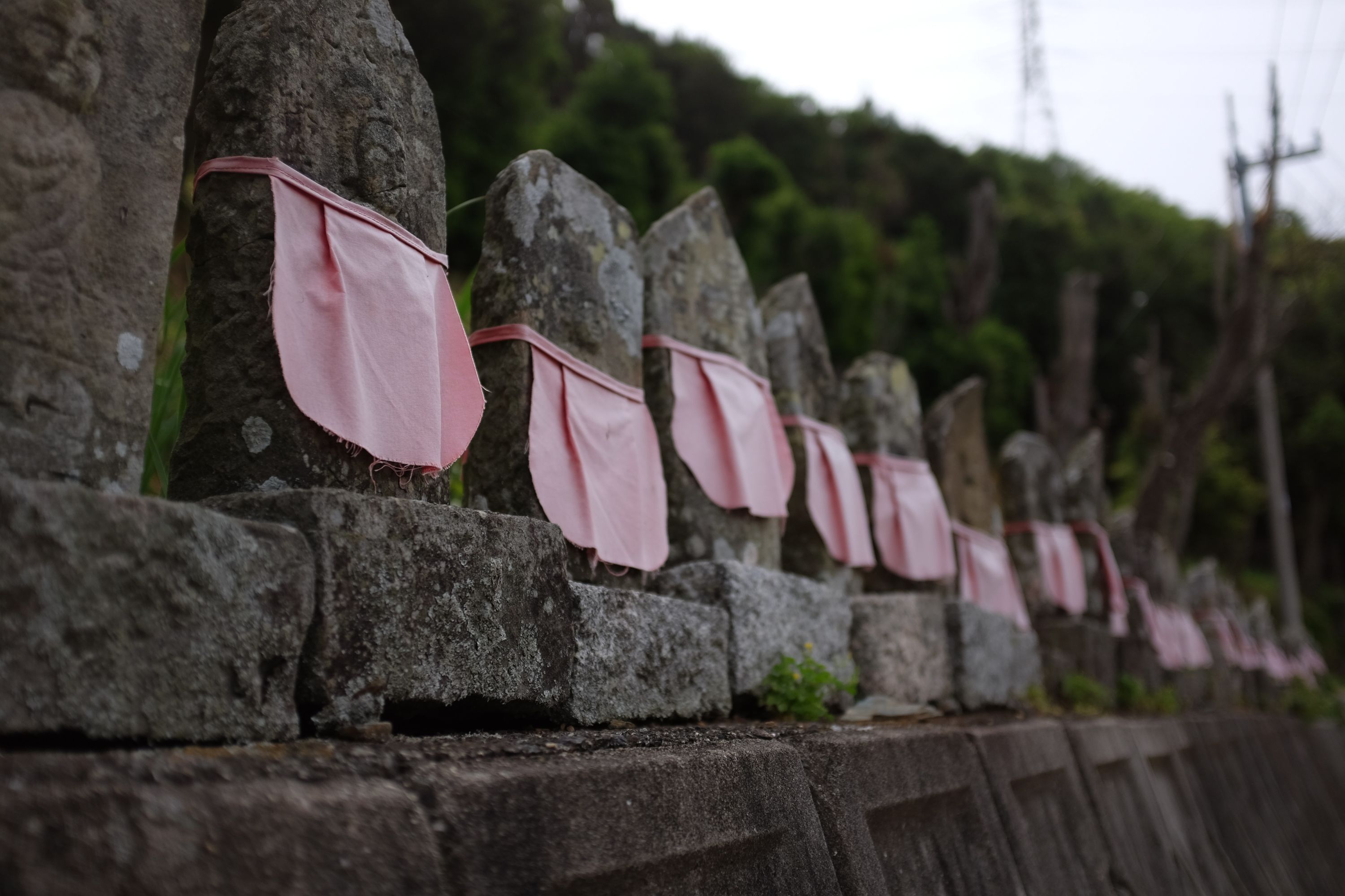 Roadside Buddhist statues wearing pink aprons.