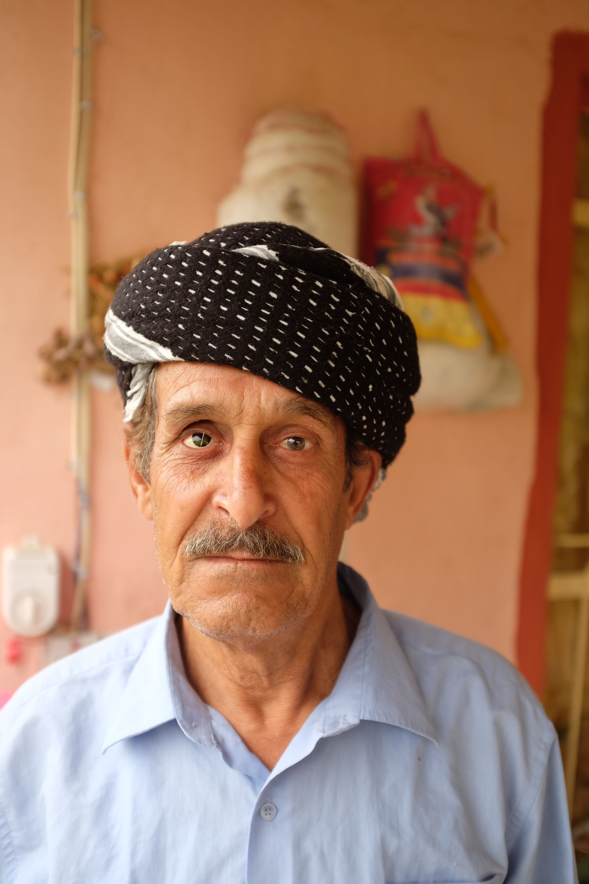 A one-eyed man wearing a turban looks into the camera.