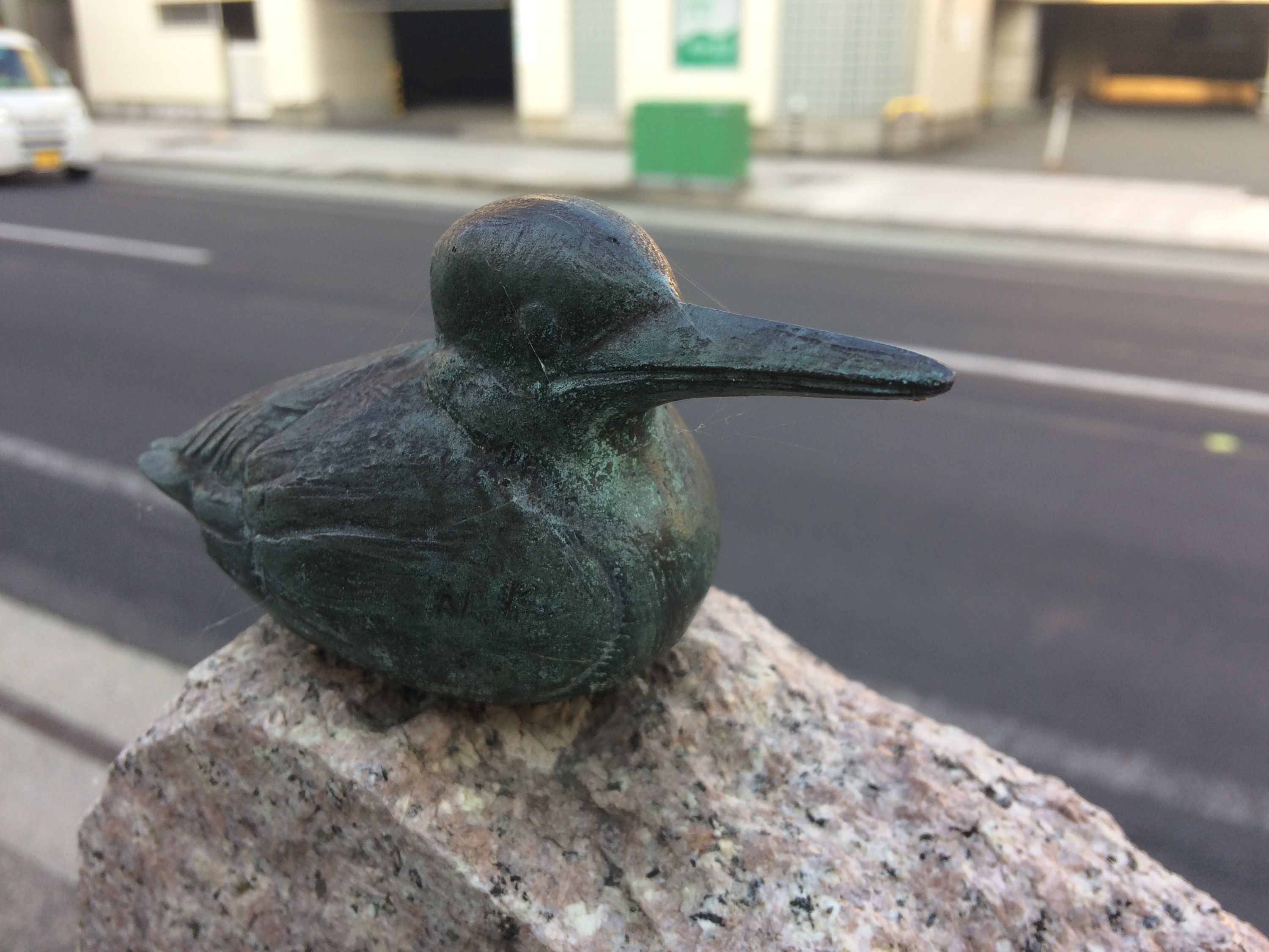 An unhappy statue of a kingfisher by the side of a road.
