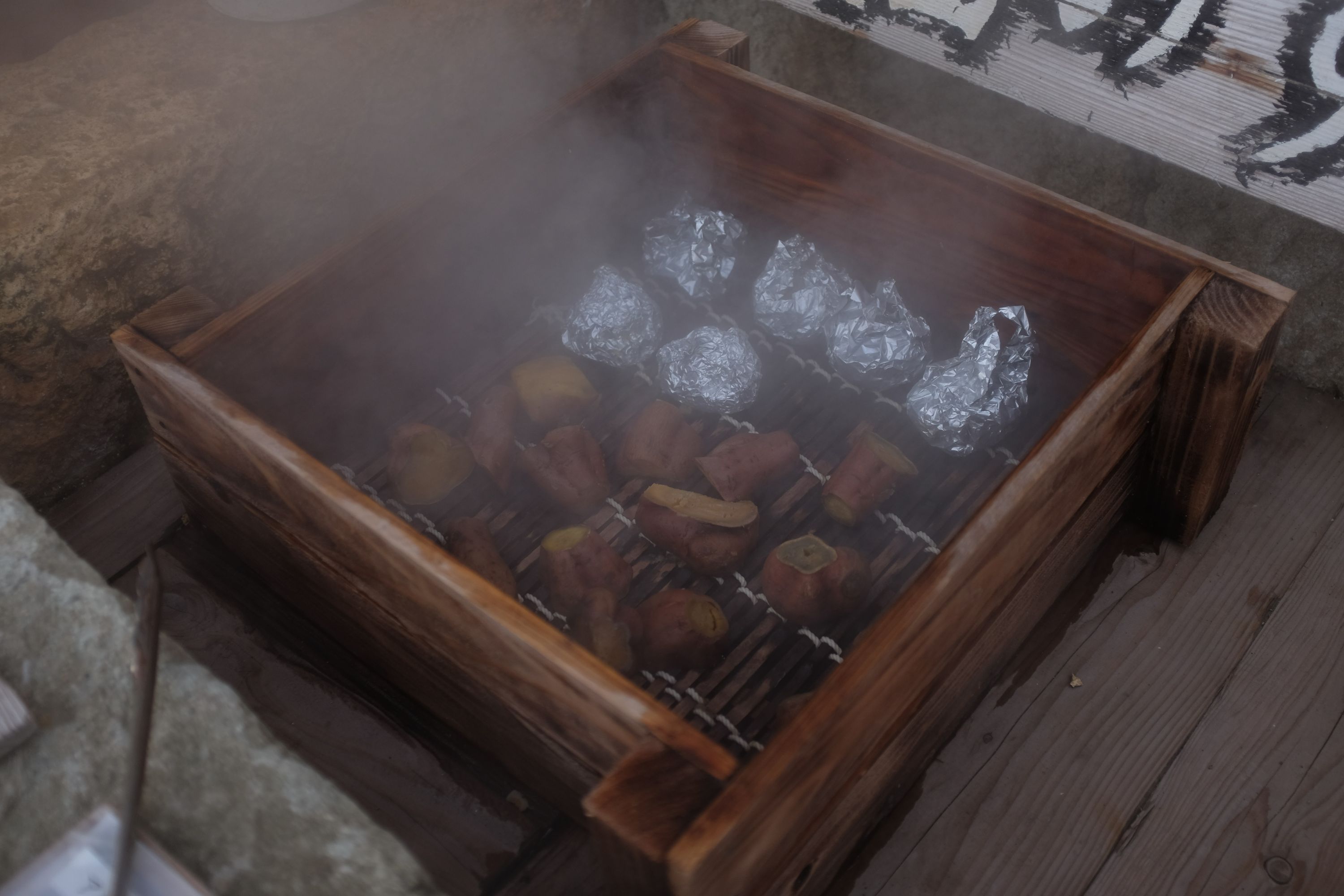 Sweet potatoes and onions being steamed in a wooden crate at a hot spring.