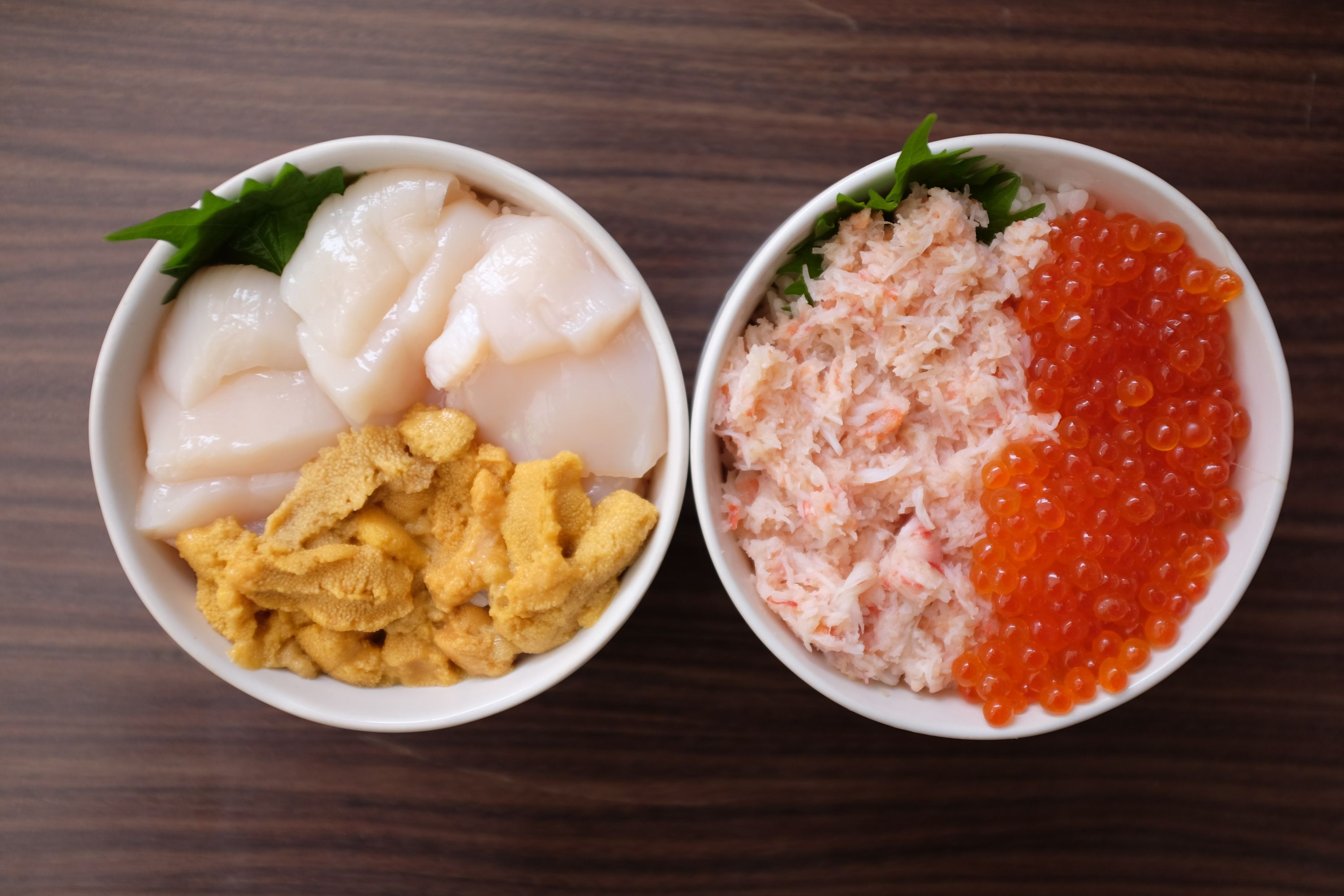 Two large bowls of seafood: scallops and sea urchin in one, crab meat and salmon roe in the other.