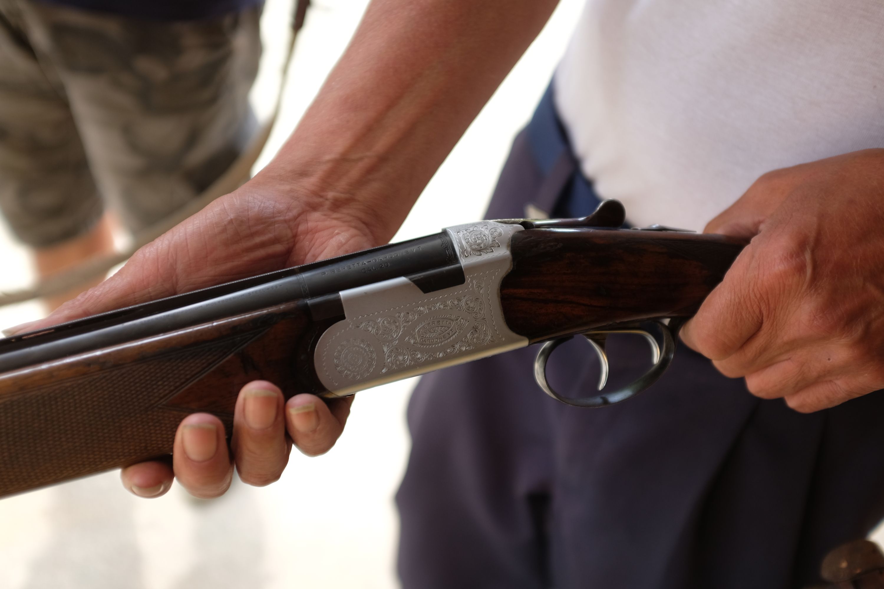 Closeup of a man’s hands holding a Beretta shotgun.