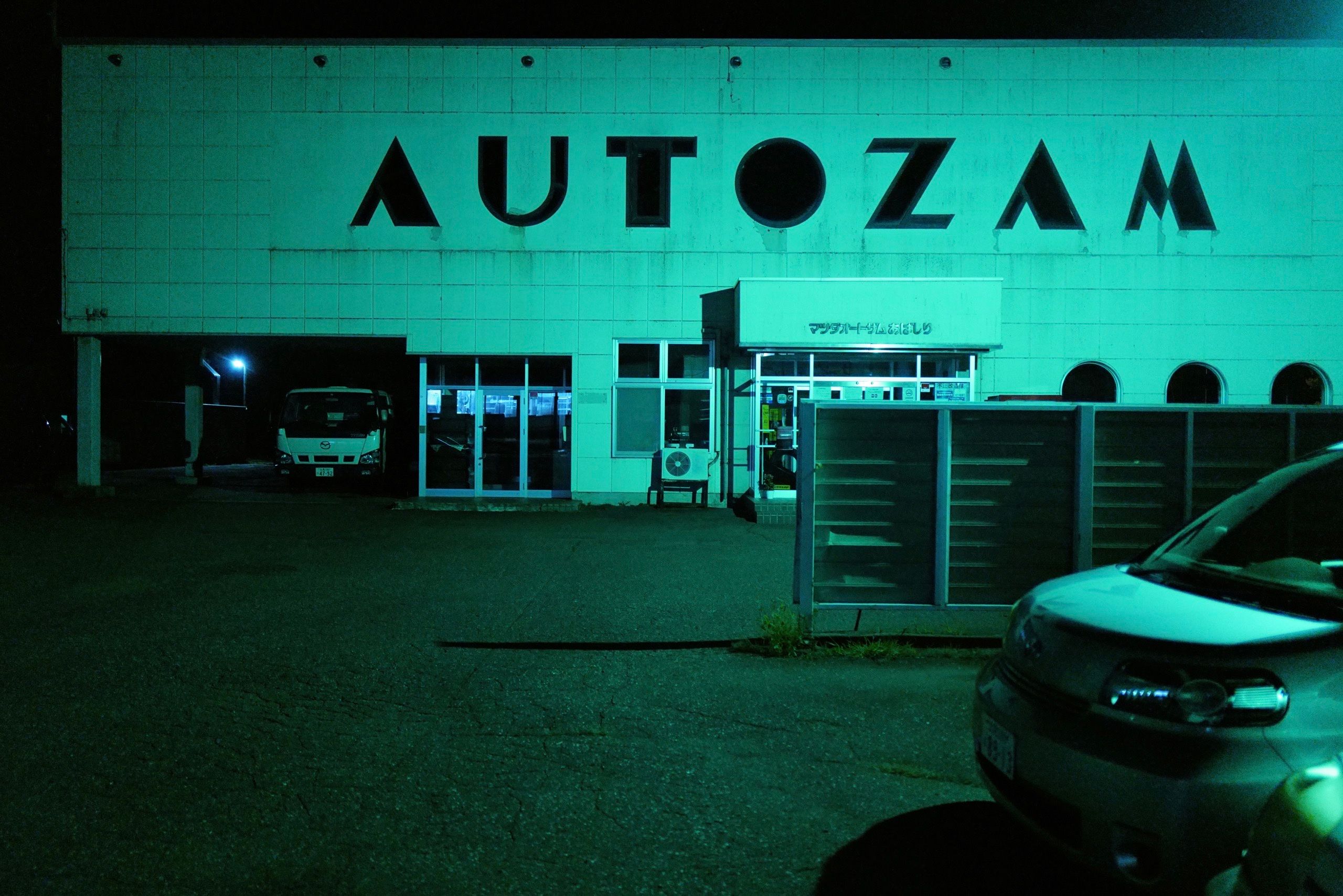 A sign on a building in the night says AUTOZAM