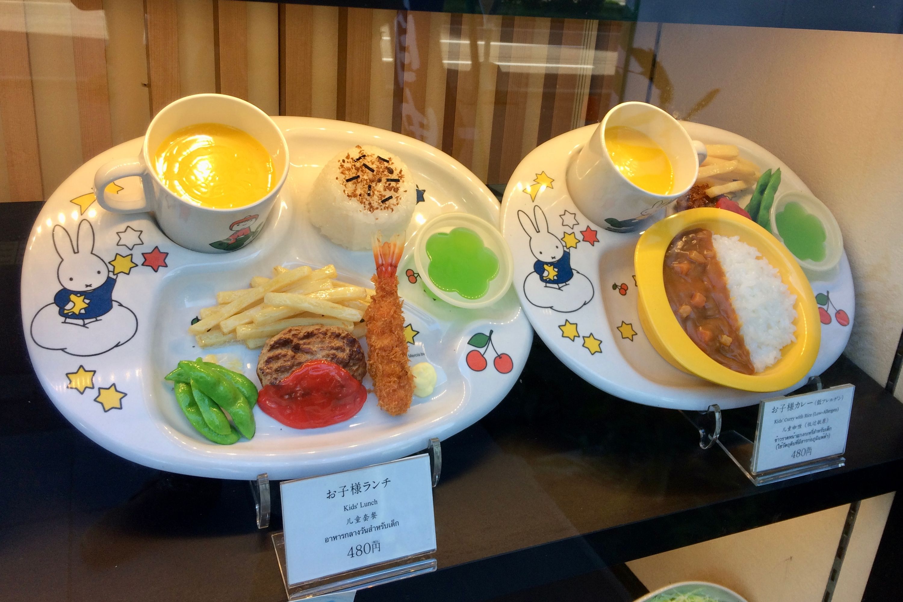In the window of a restaurant, plastic kids’ meals set on Miffy-themed trays.