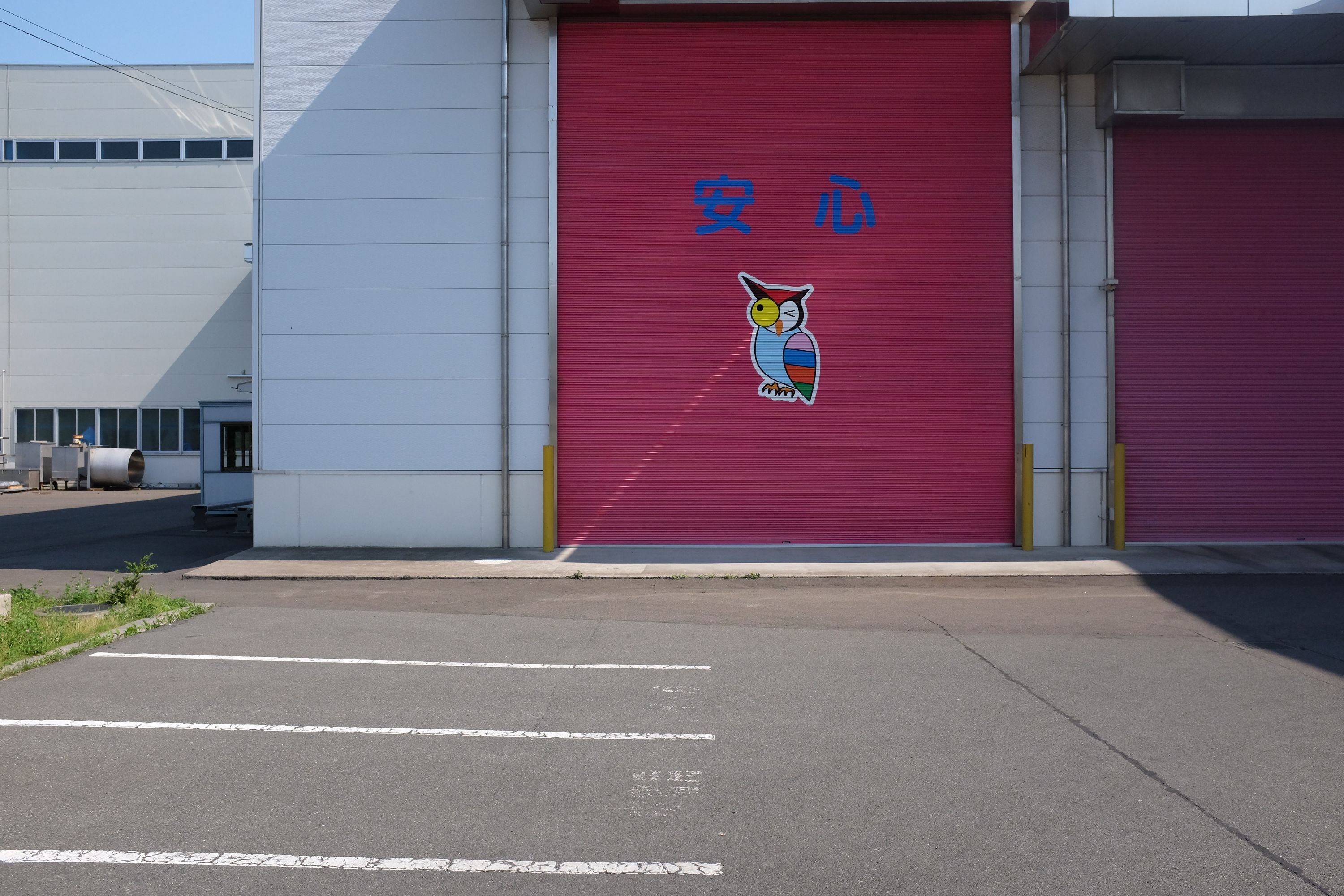 On a warehouse door marked with the word 安心, Japanese for peace of mind, a ray of light combines with the painting of an owl to make it appear that the light is coming from the owl’s bulging right eye.