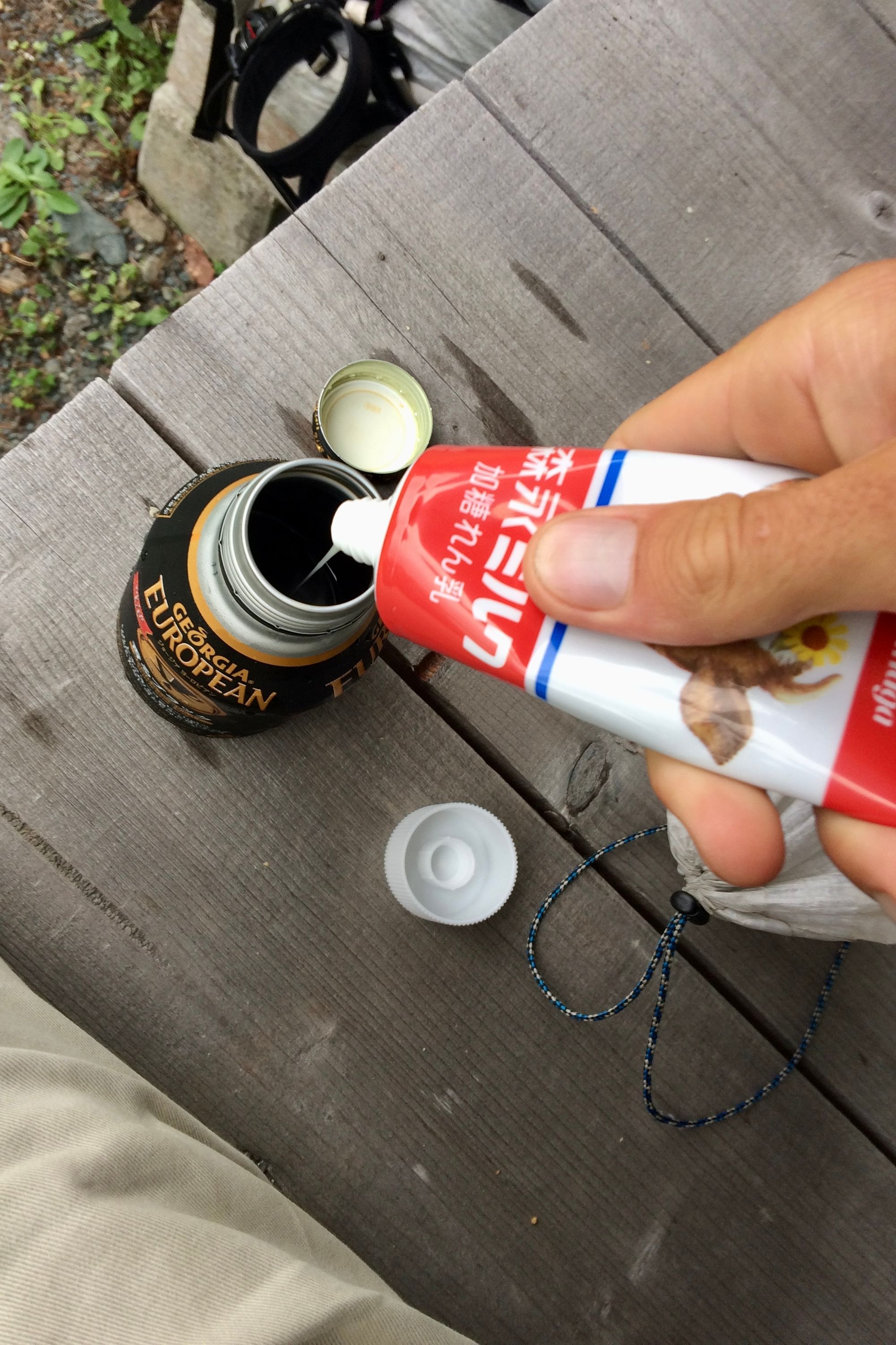 The author squeezes condensed milk into a metal can of coffee.