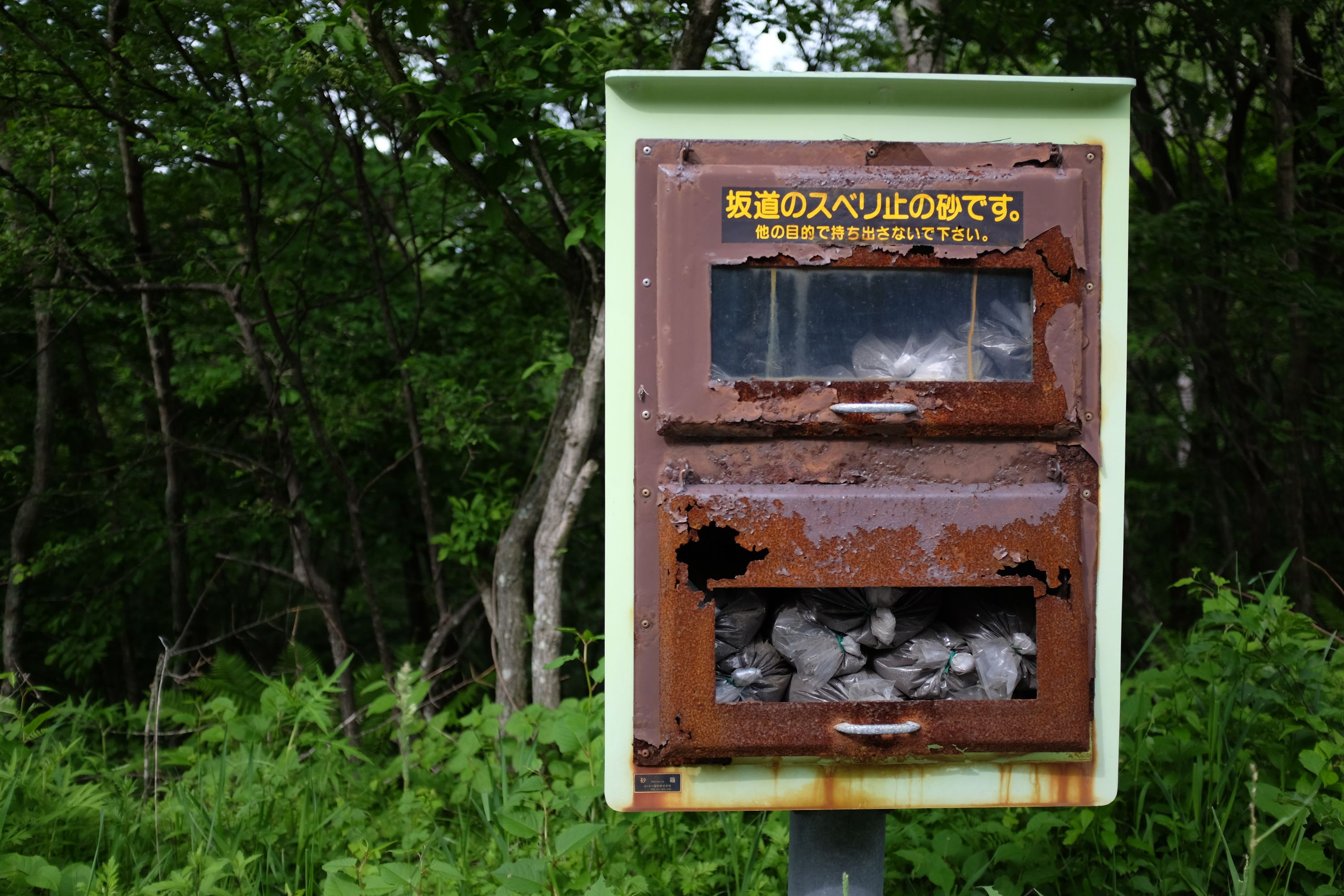A rusty cabinet in the forest with bags of volcanic ash.