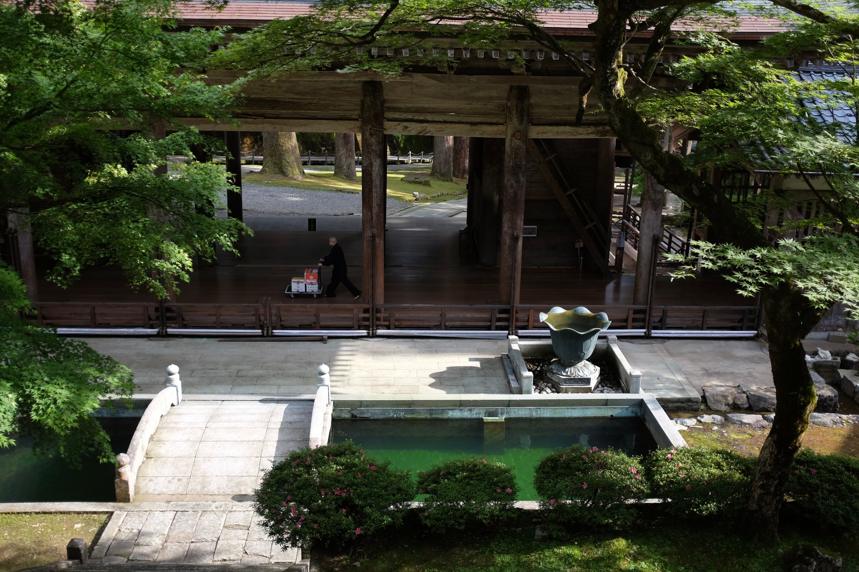 A monk pushes a cart across the courtyard of a Japanese temple.